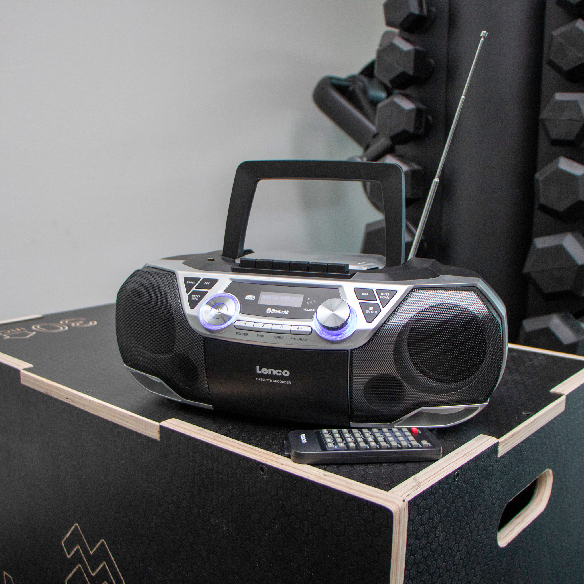 Boombox noir et argent sur une boîte noire et blanche. Une télécommande sur la boîte.
