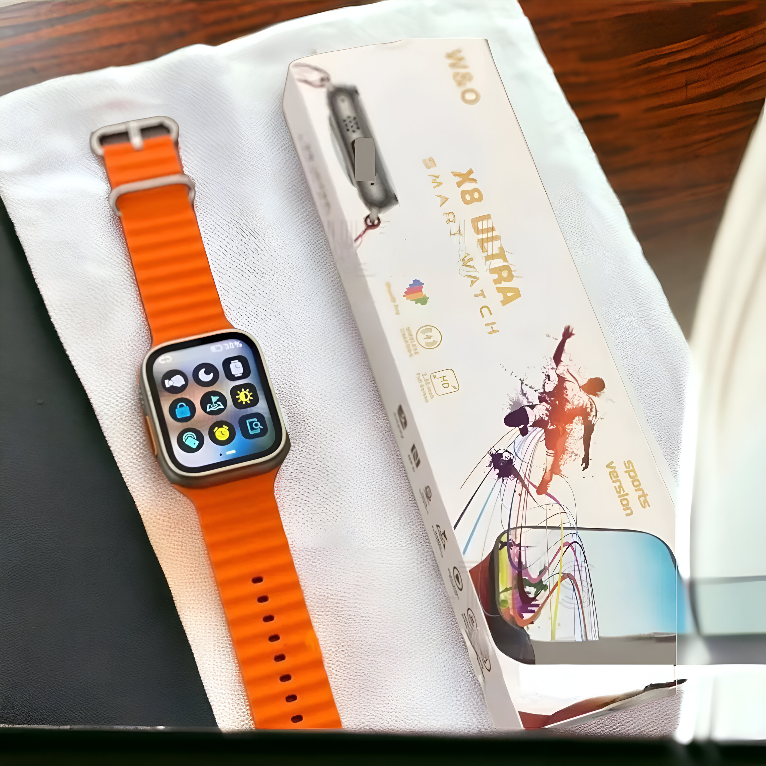 Smartwatch con correa naranja, toalla blanca y caja del producto con un hombre.