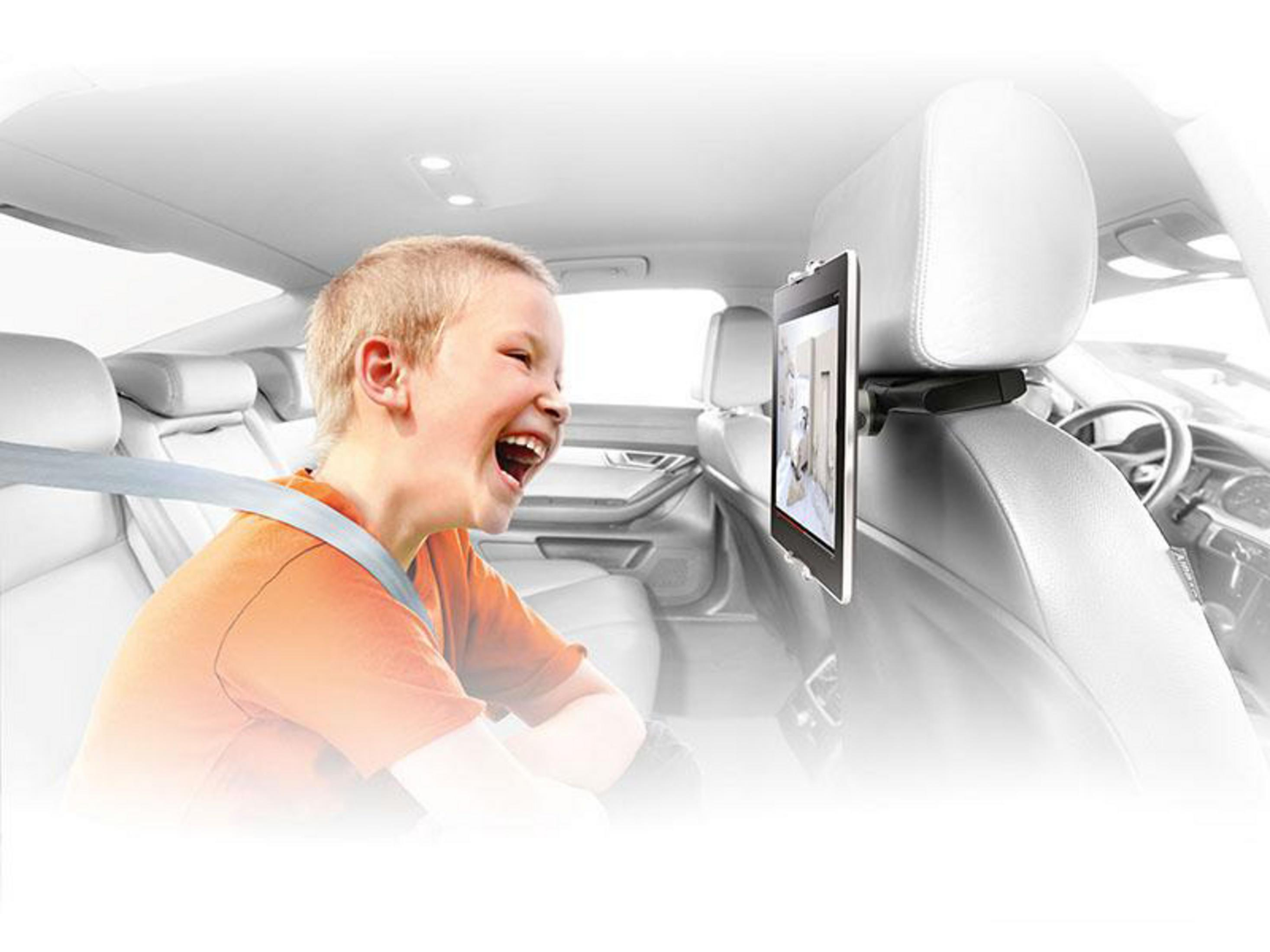 Dziecko śmieje się podczas oglądania tabletu zamontowanego na zagłówku samochodu.