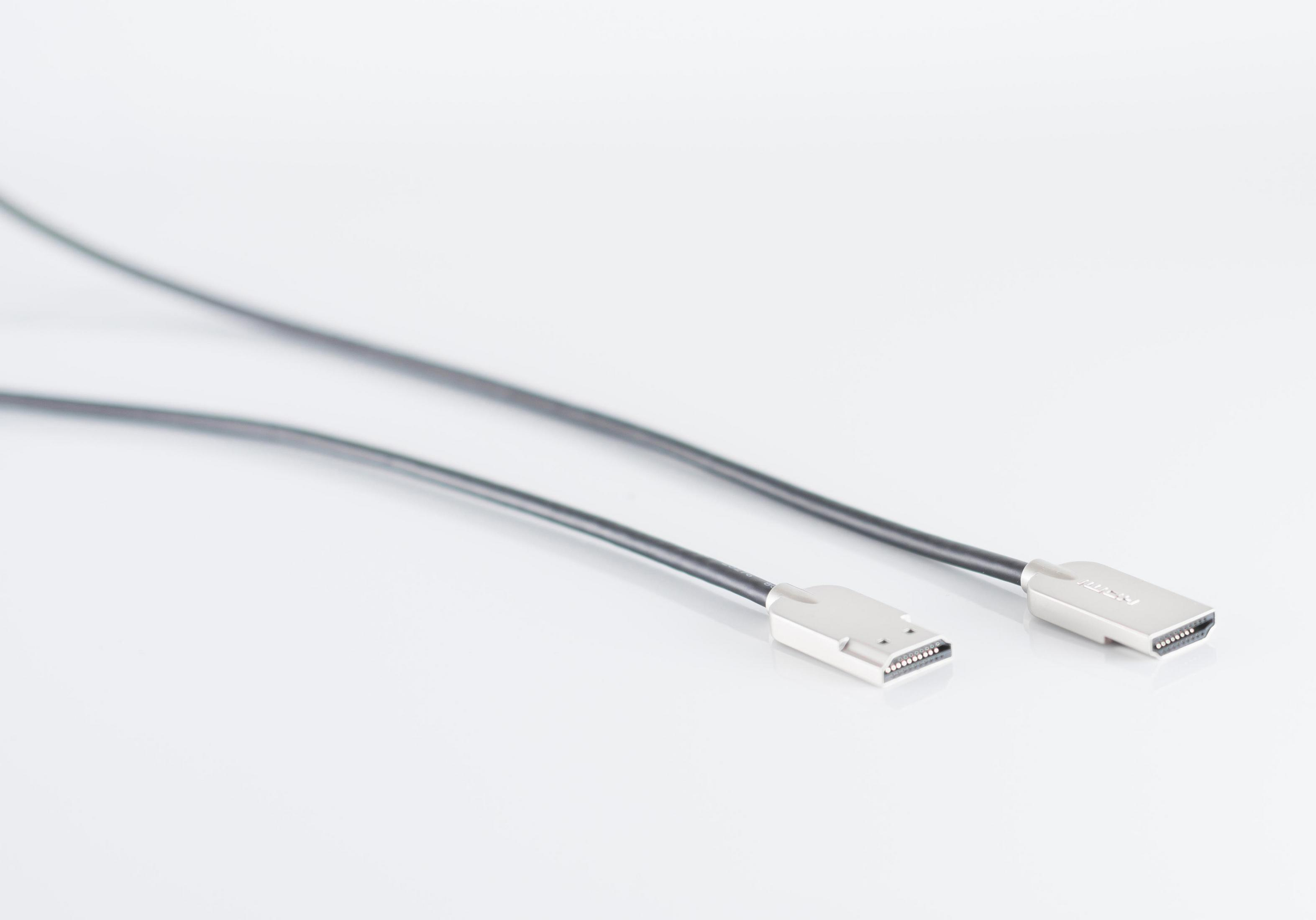 Zwei schwarze HDMI-Kabel mit silbernen Steckern auf weißer Oberfläche. Die Kabel sind fokussiert.