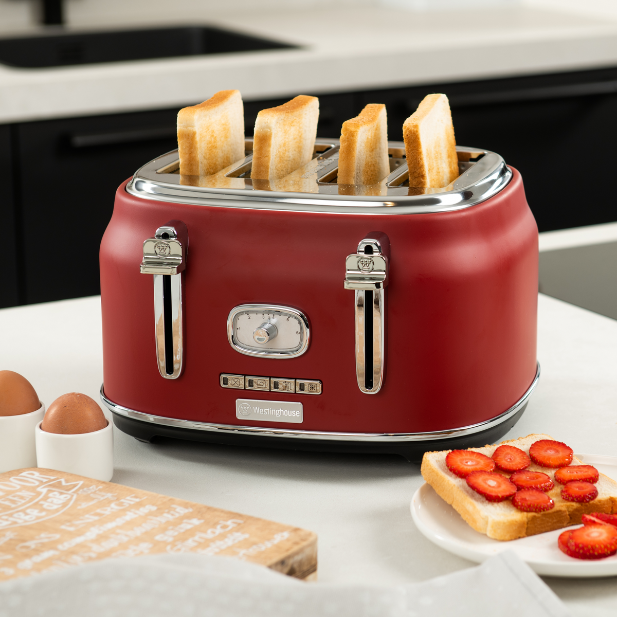Roter Toaster mit Toast und Eiern auf weißer Oberfläche.