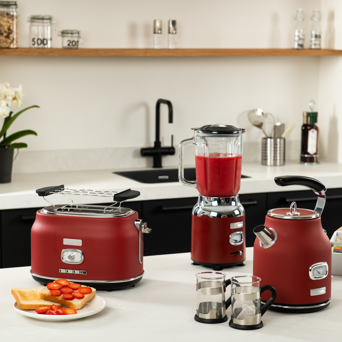 Küchentheke mit rotem Toaster, Wasserkocher und Mixer. Toast mit Erdbeeren auf einem Teller.