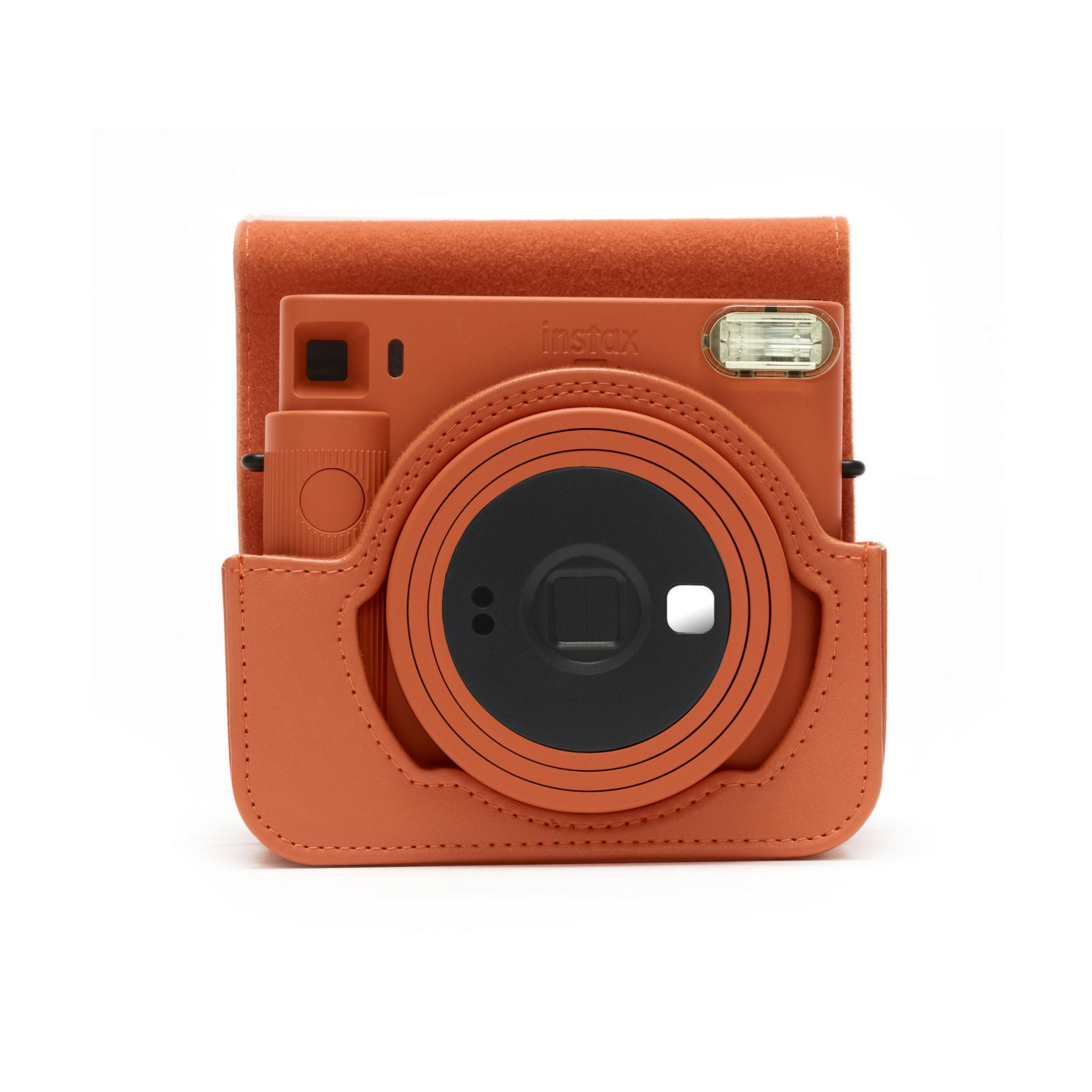 Una cámara Instax naranja en una funda a juego. La cámara está cerrada.