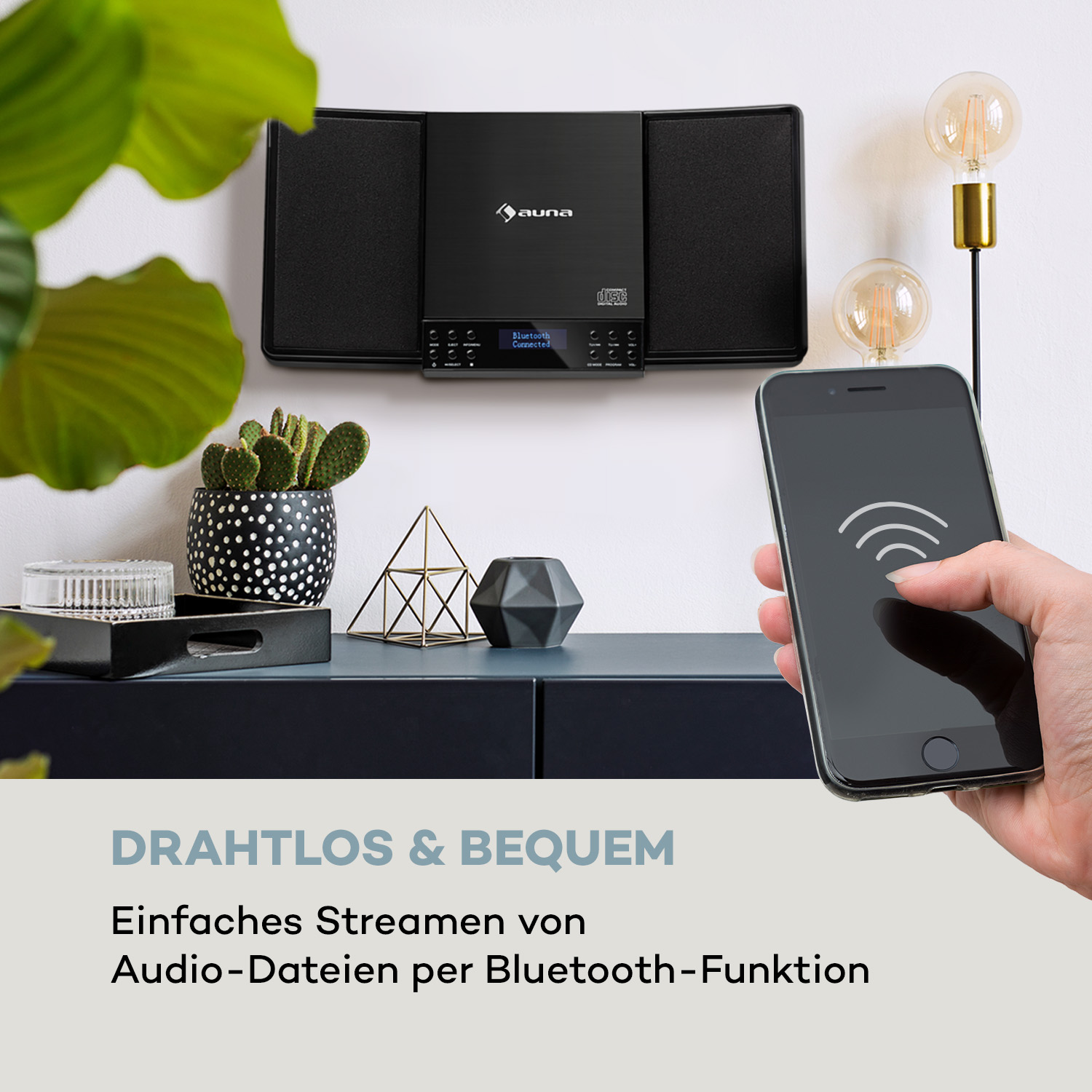 Schwarzes Auna Audiosystem mit Telefon auf dem Tisch. Pflanze und Deko.