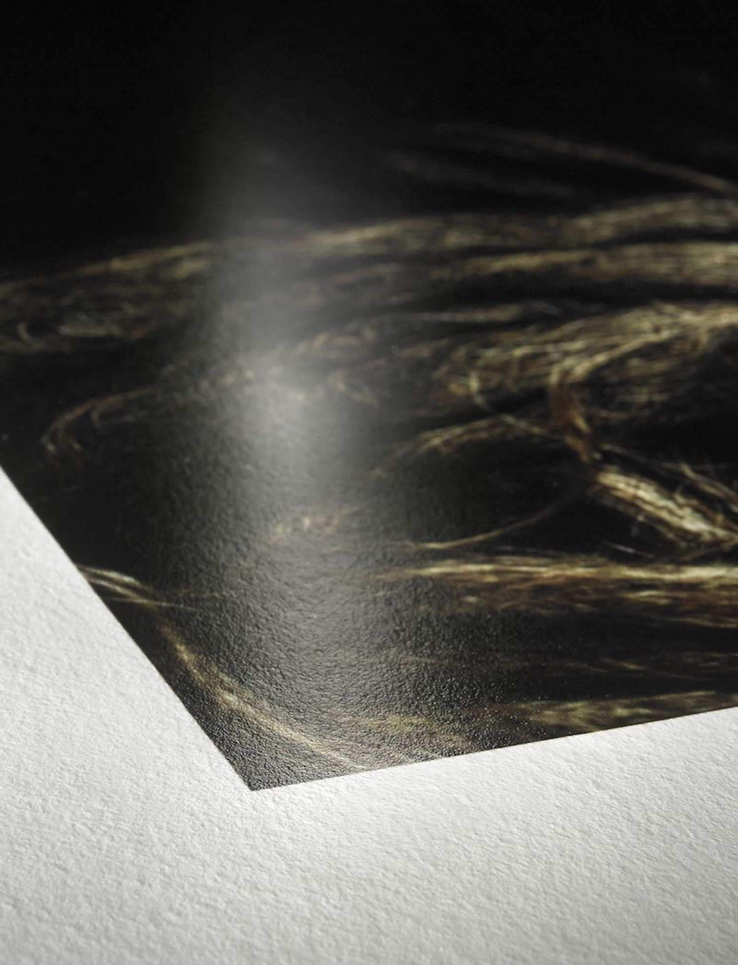 Nahaufnahme einer glänzenden Fotoausdruckkante, zeigt die Ecke und Textur von Papier und Druck.