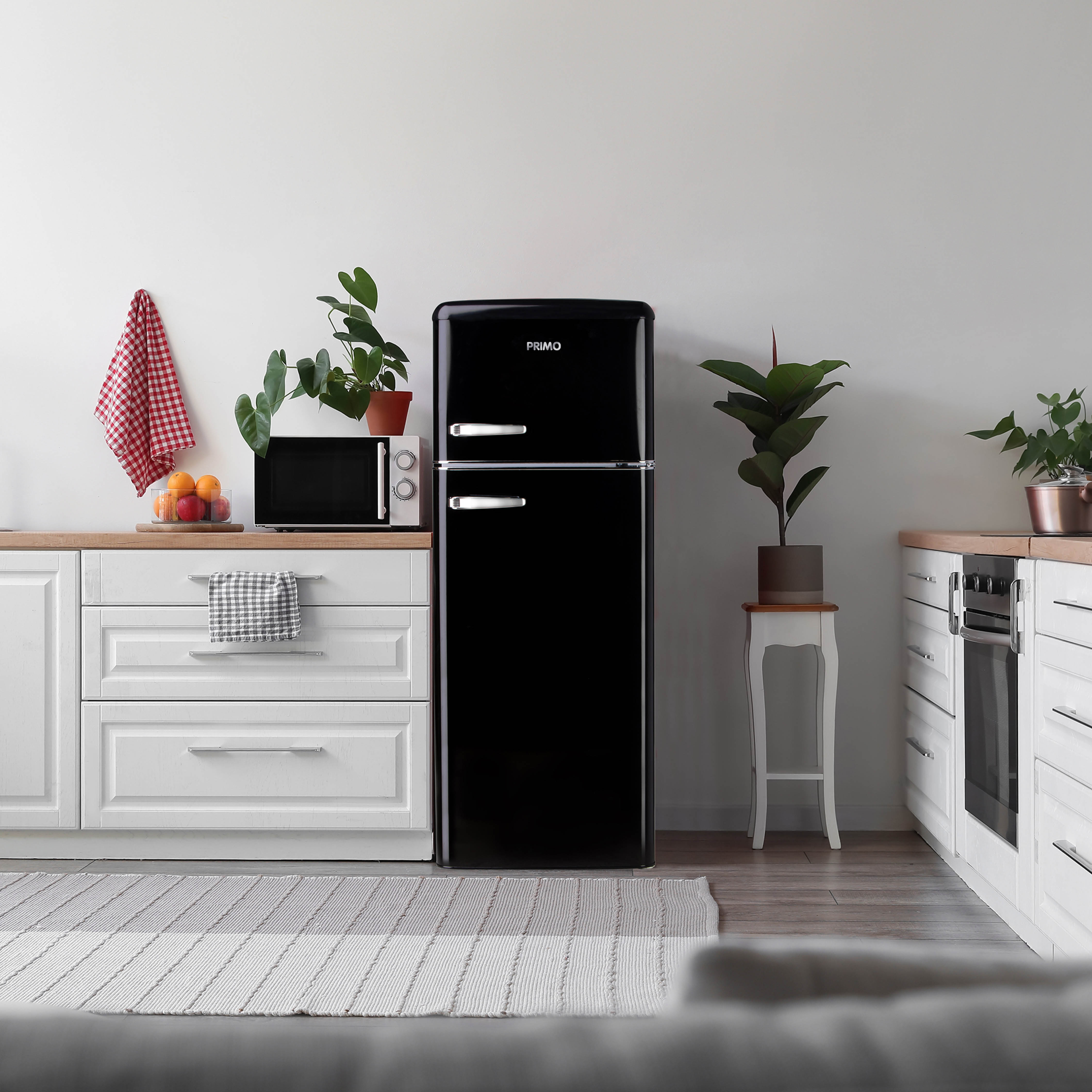 Réfrigérateur rétro noir dans une cuisine avec des meubles blancs, des plantes et de la décoration.