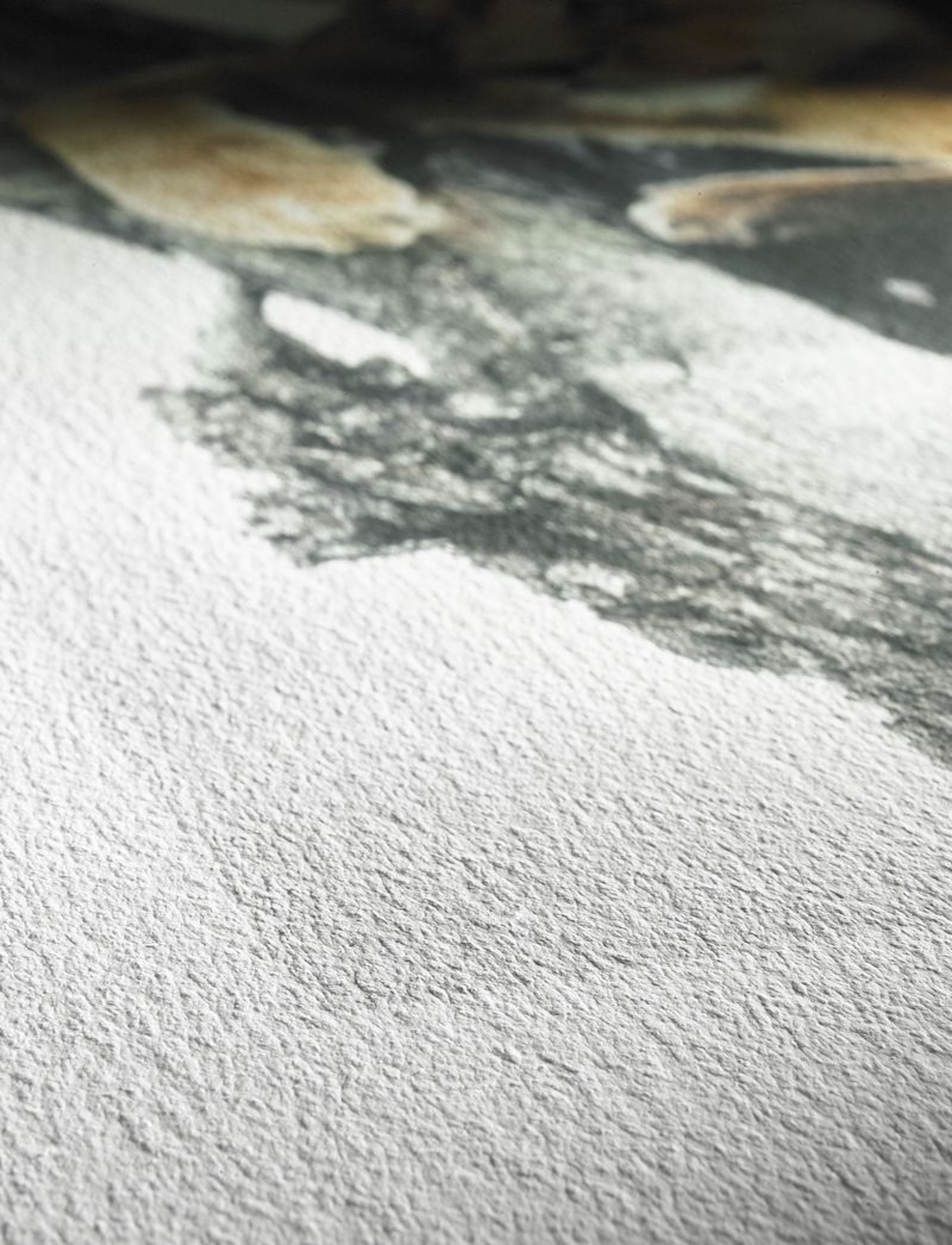 Nahaufnahme einer strukturierten Papieroberfläche. Das Papier hat eine hellgraue Farbe und feine Muster.