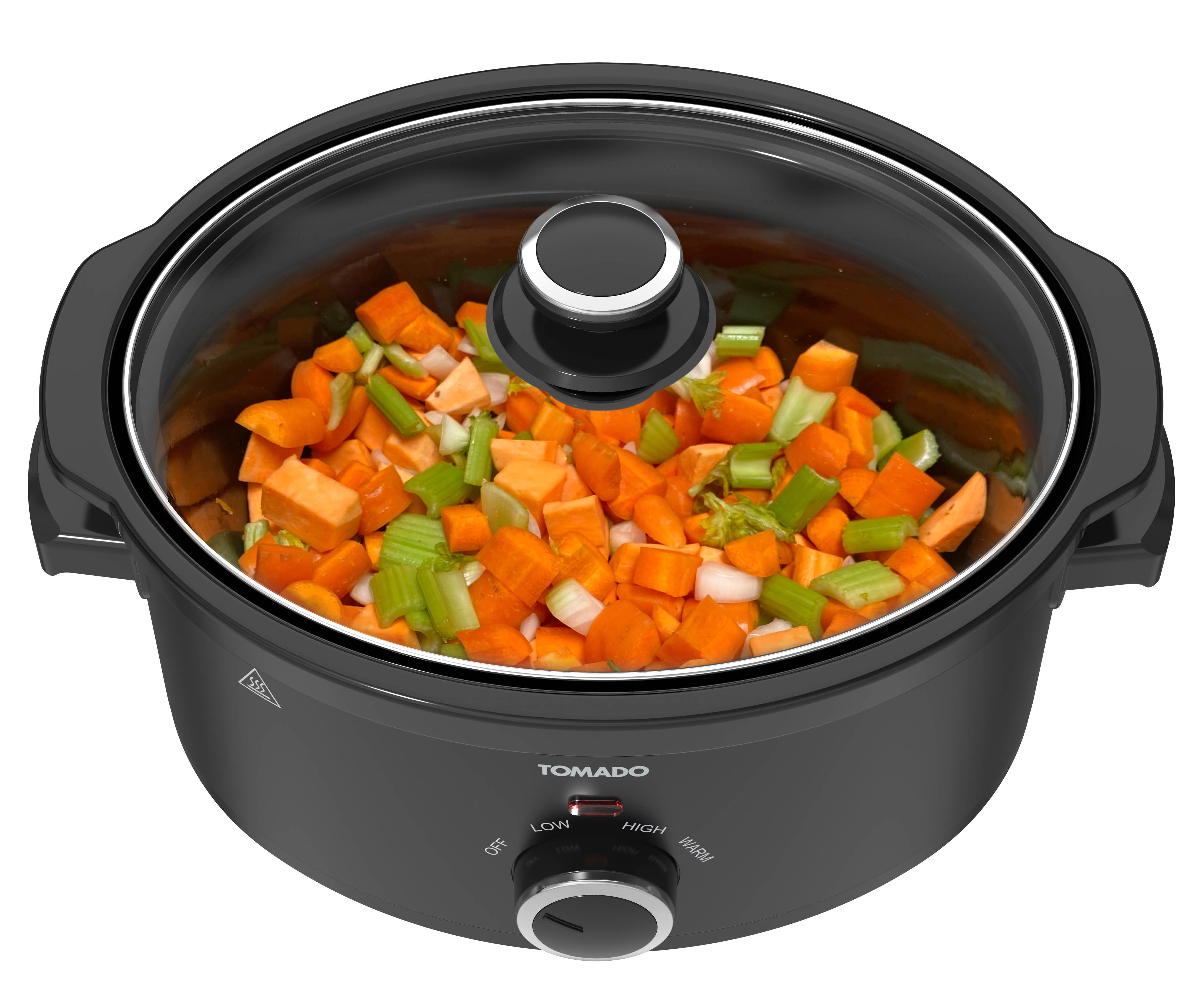 Black Tomado slow cooker with a glass lid. It contains chopped vegetables. It is on a white surface.