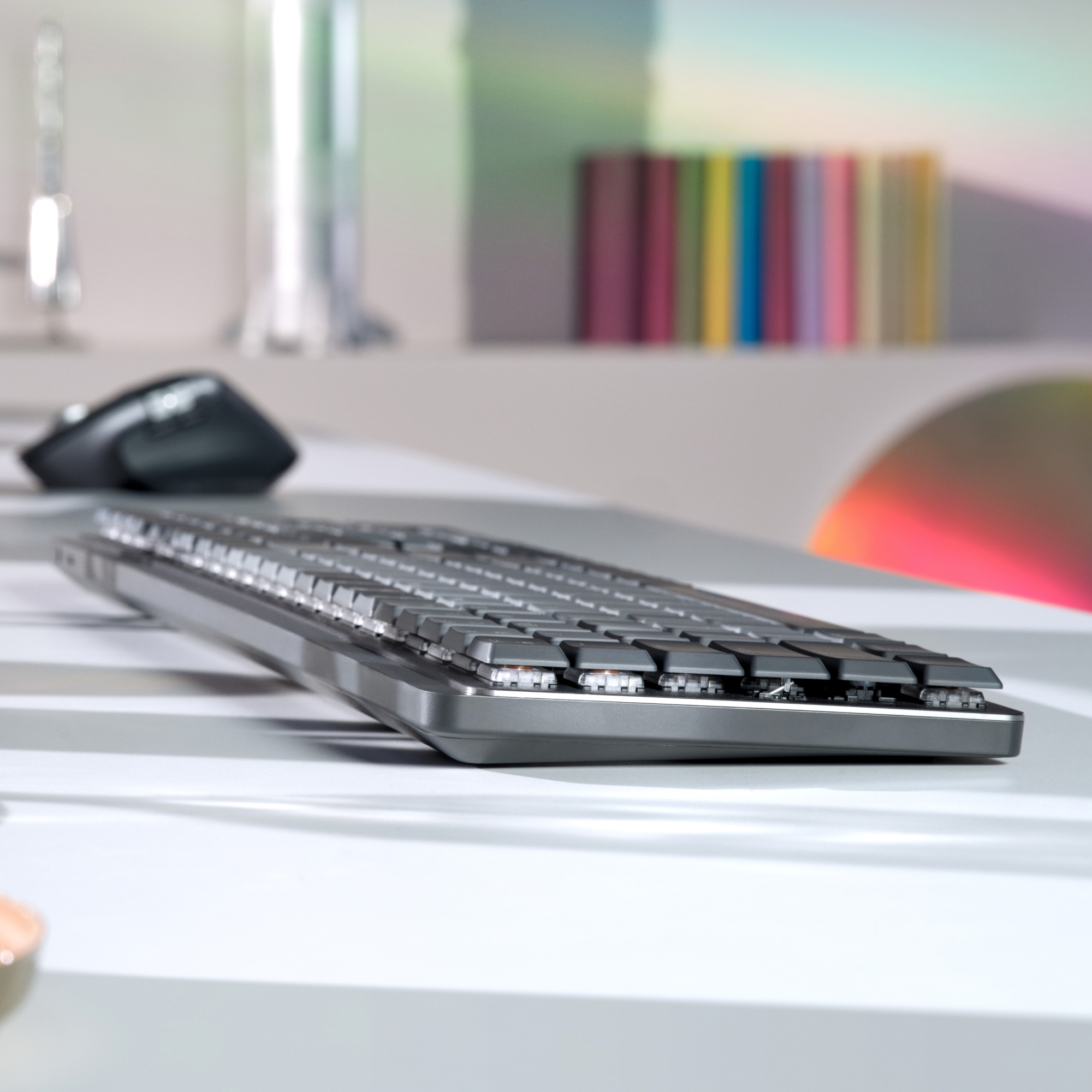 Klawiatura na biurku z myszą i innymi przedmiotami, kolorowe tło.