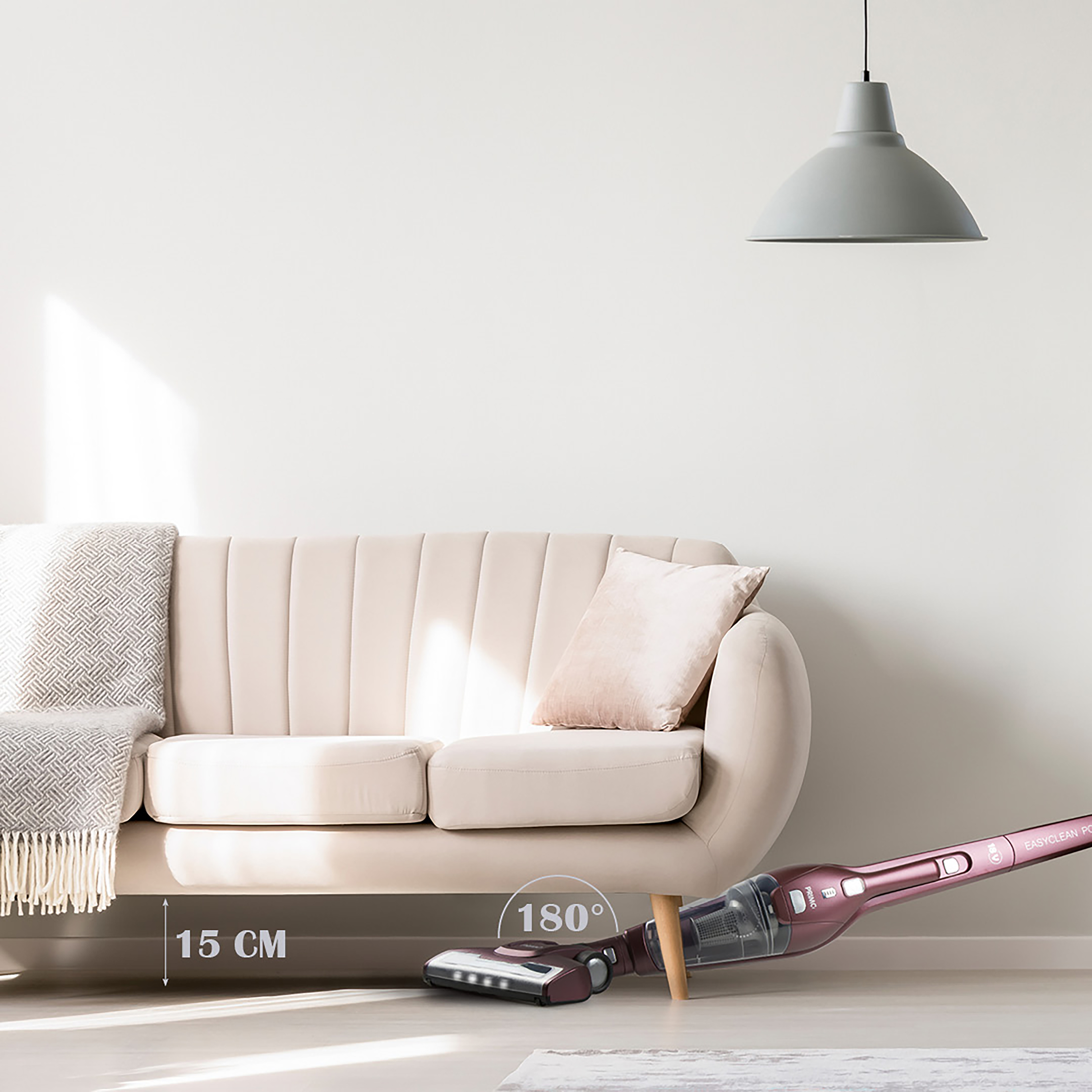 Aspirateur nettoyant sous un canapé, montrant un dégagement de 15 cm.