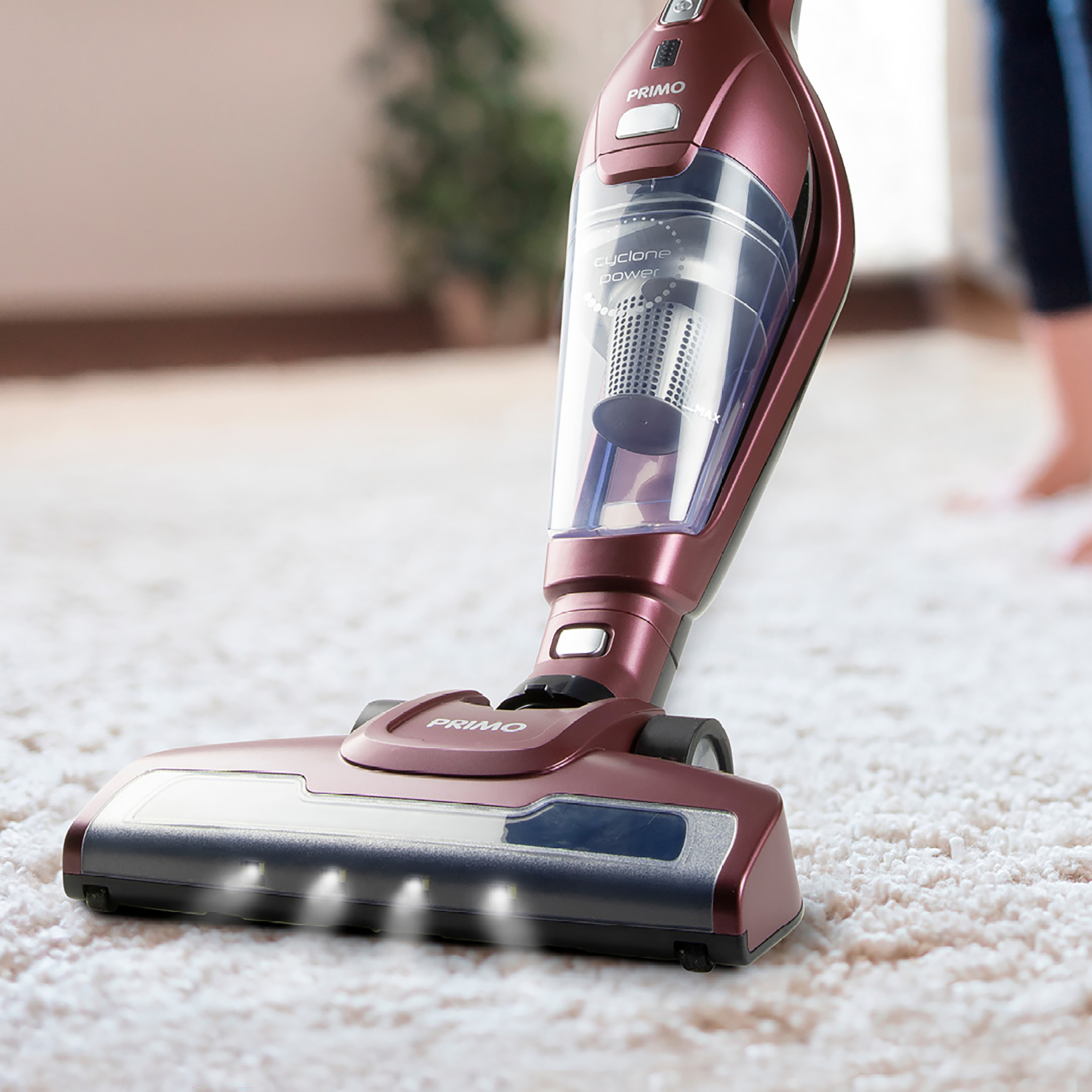 Un aspirateur rouge et argenté sur un tapis blanc. L'aspirateur a une barre lumineuse à l'avant.