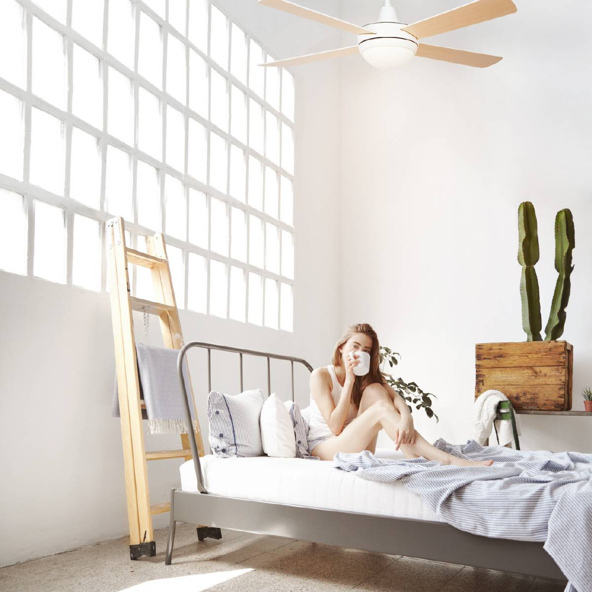 Donna sul letto con tazza, stanza luminosa. Scala in legno, pianta e finestra. Sfondo bianco.