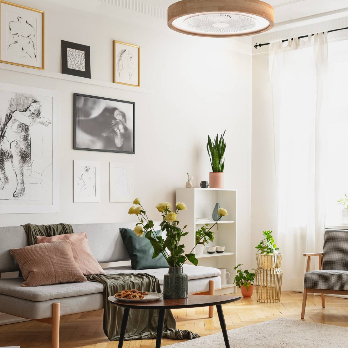 Salón con ventilador de techo, obras de arte, sofá, mesa de centro y plantas.