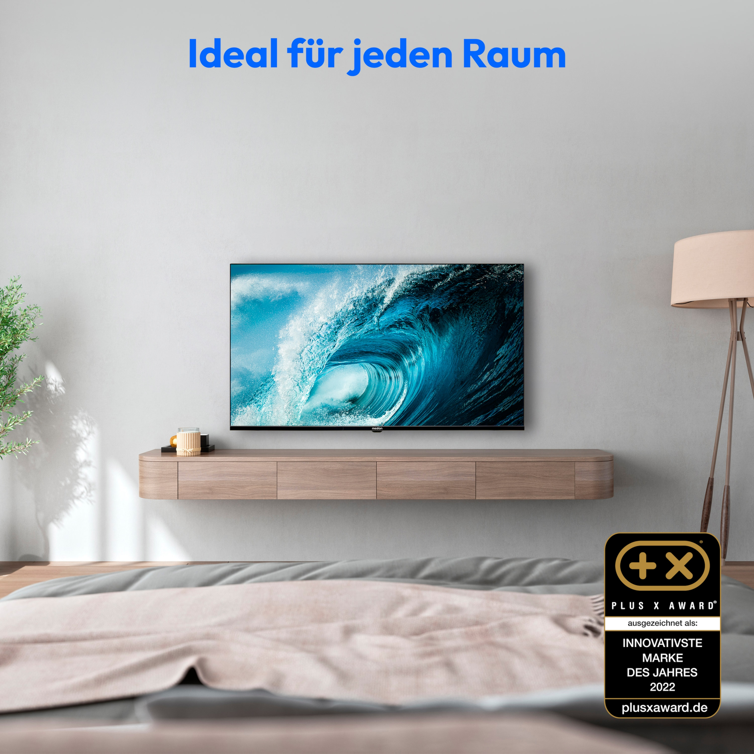 Modernes Wohnzimmer mit einem Fernseher an der Wand. Ein Bett und eine Lampe sind im Vordergrund.