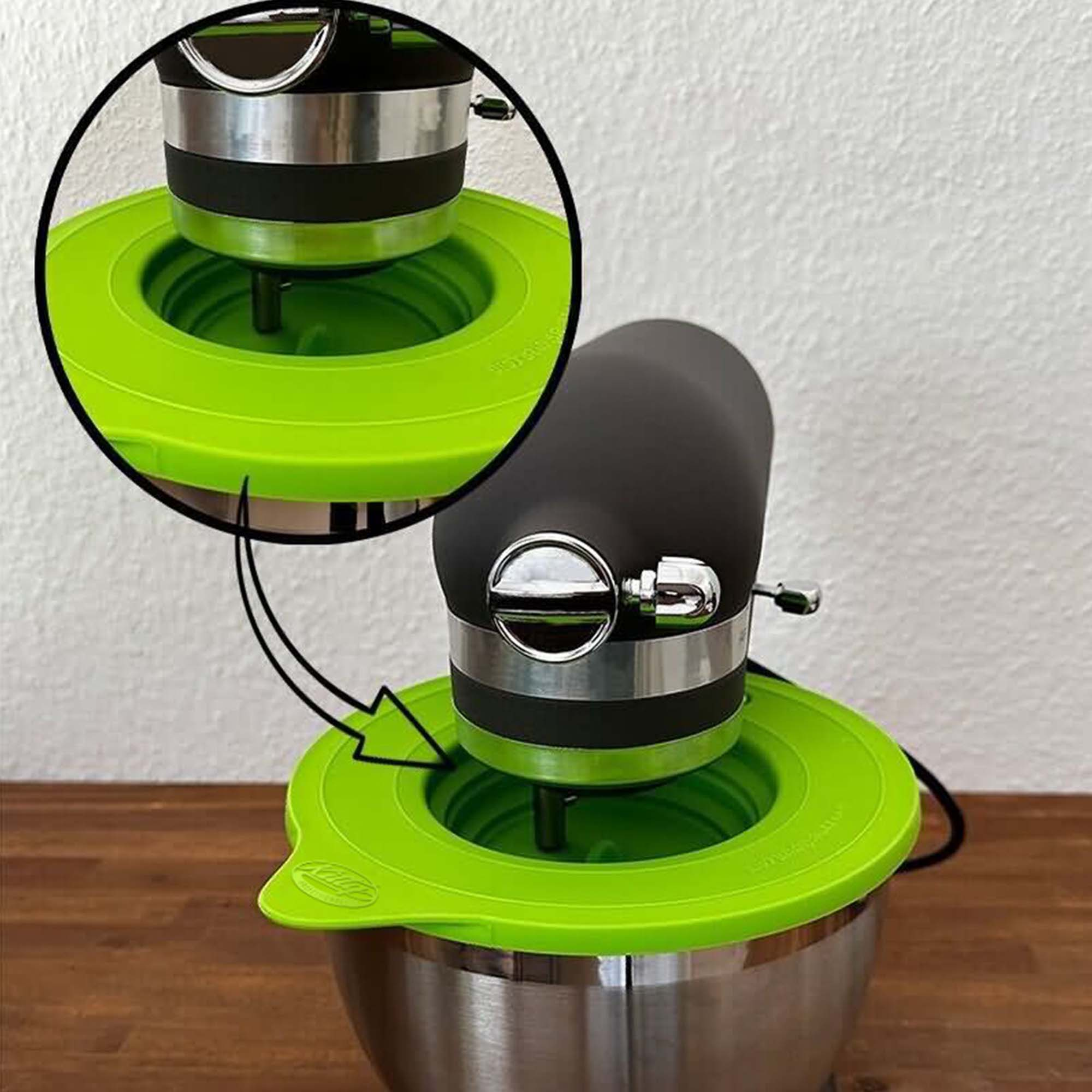 Schwarzer und silberner Küchenmixer mit grünem Deckel auf der Schüssel. Vergrößerter Kreis zeigt Deckeldetails.