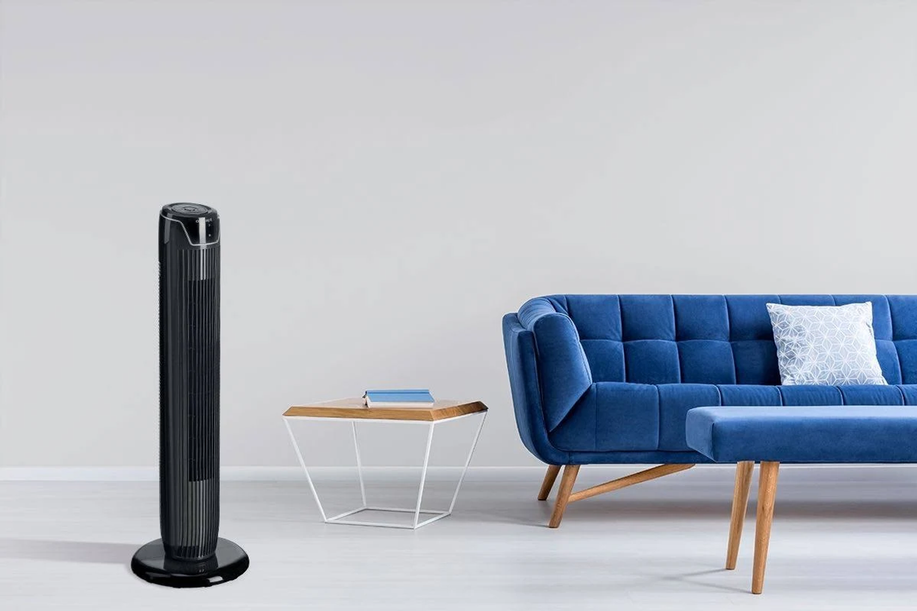 Un ventilador de torre negro está a la izquierda. Un sofá azul y una mesa a la derecha. Fondo blanco.