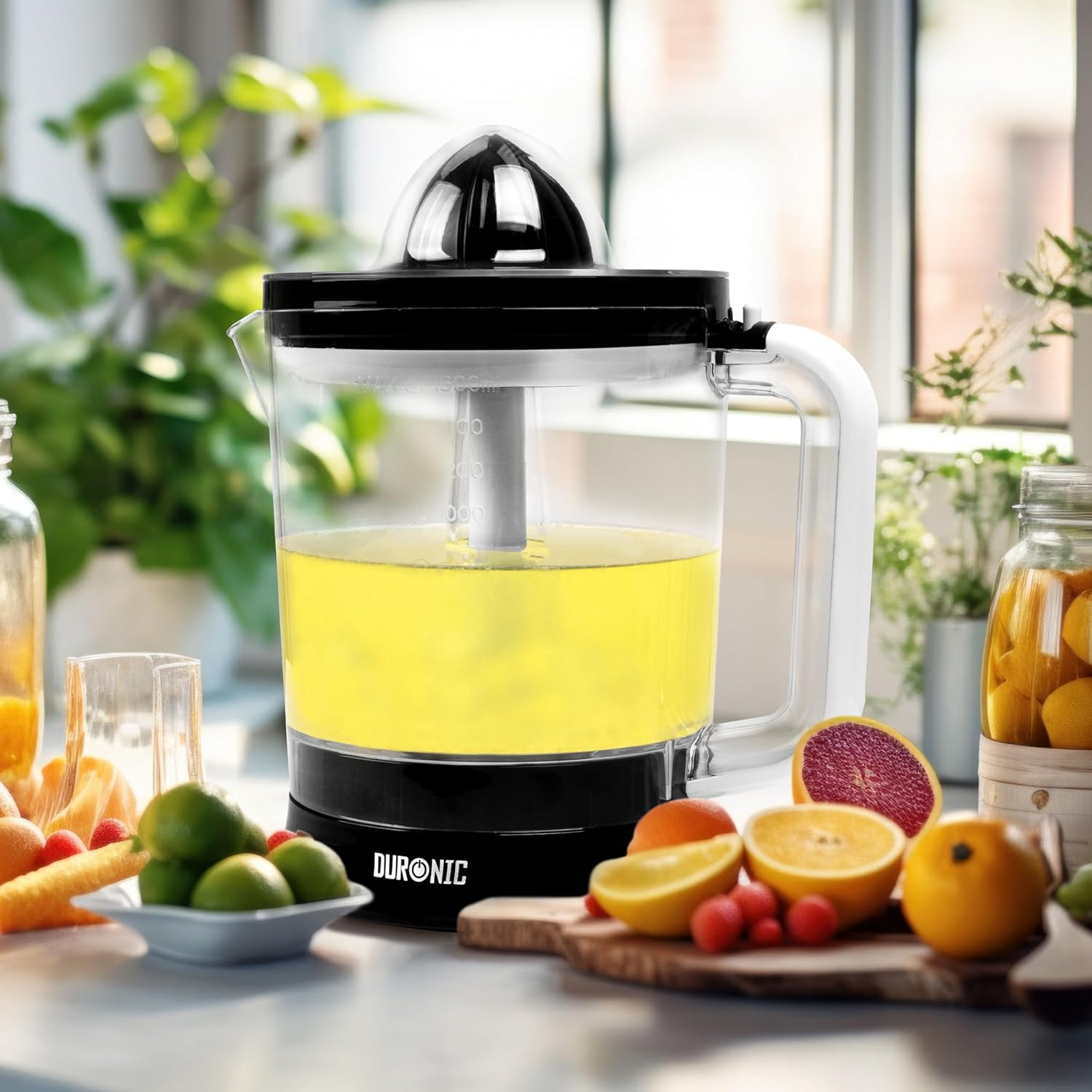 Exprimidor con jugo de naranja, con naranjas, limas y otras frutas en la mesa.