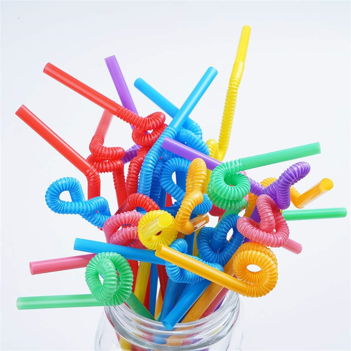 Bunte, flexible Trinkhalme in einem Glas. Mehrere Farben und Spiralformen sichtbar.