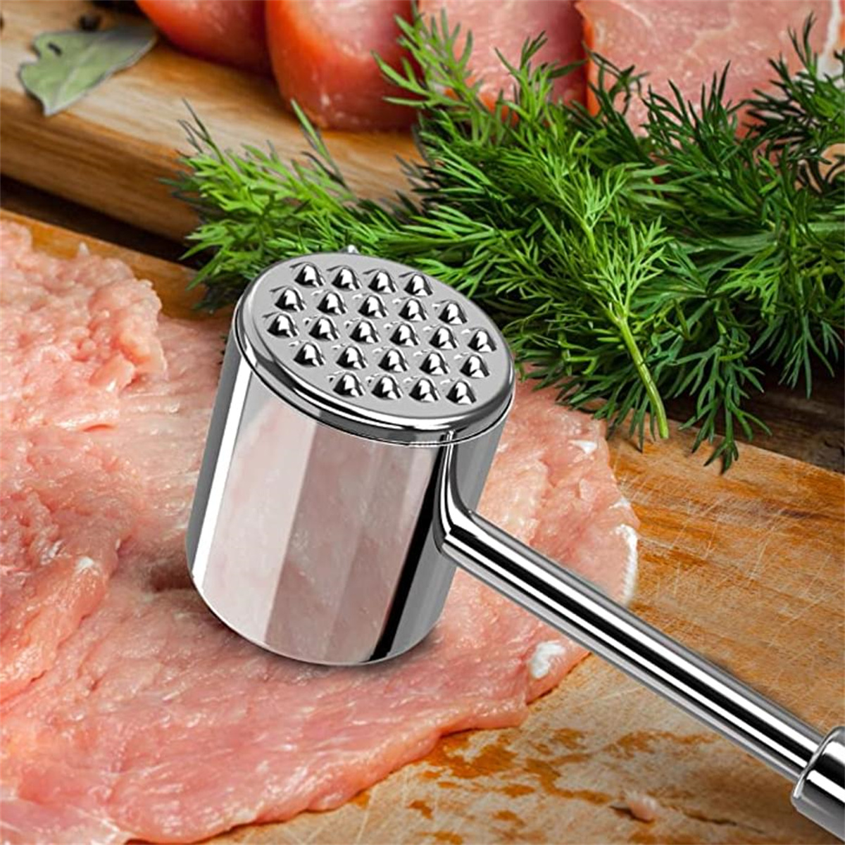 Ein Fleischklopfer liegt auf rohem Fleisch, mit frischem Dill und weiteren Fleischscheiben im Hintergrund.