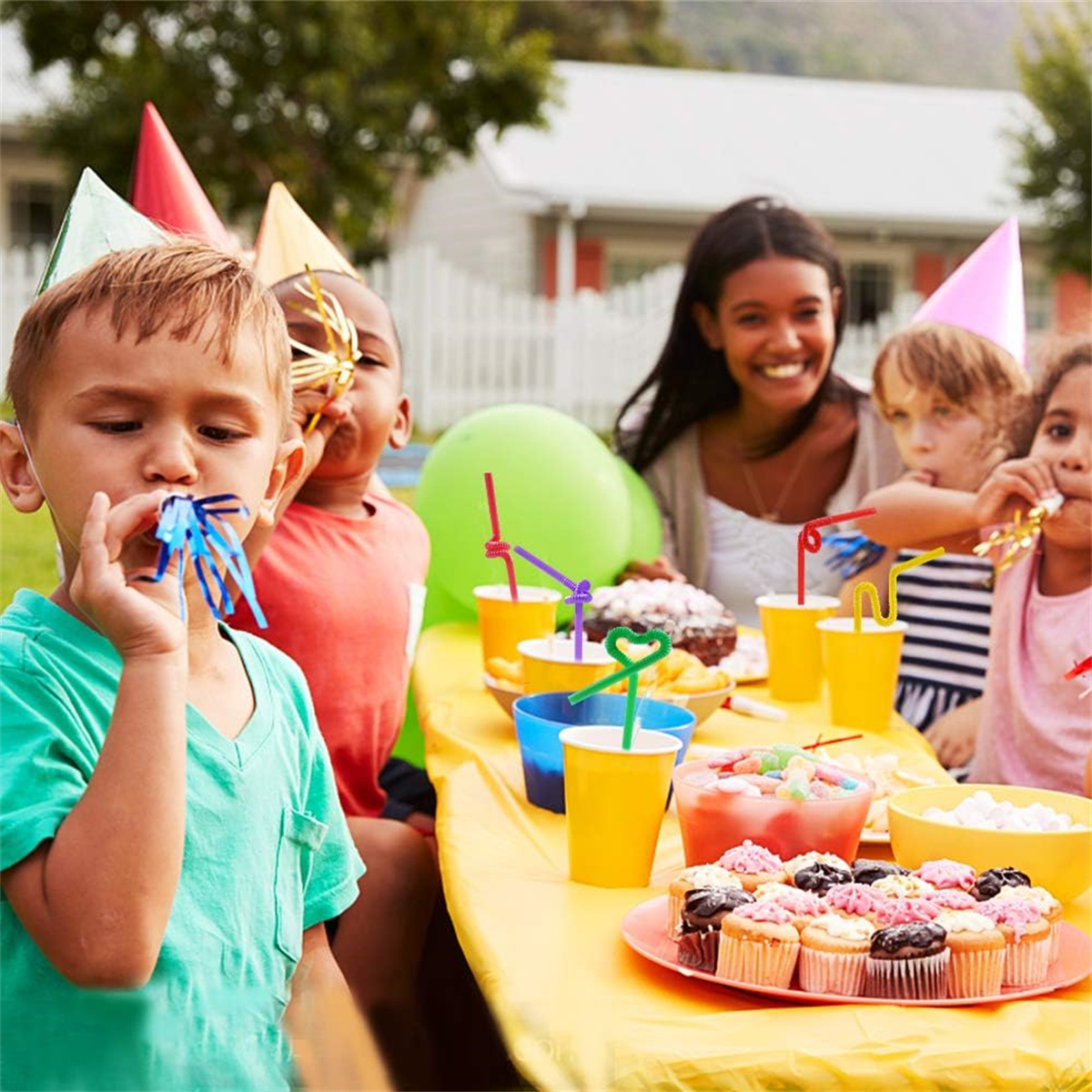 Eine Gruppe von Kindern und Erwachsenen auf einer Geburtstagsfeier, mit Kuchen und Getränken auf einem Tisch.