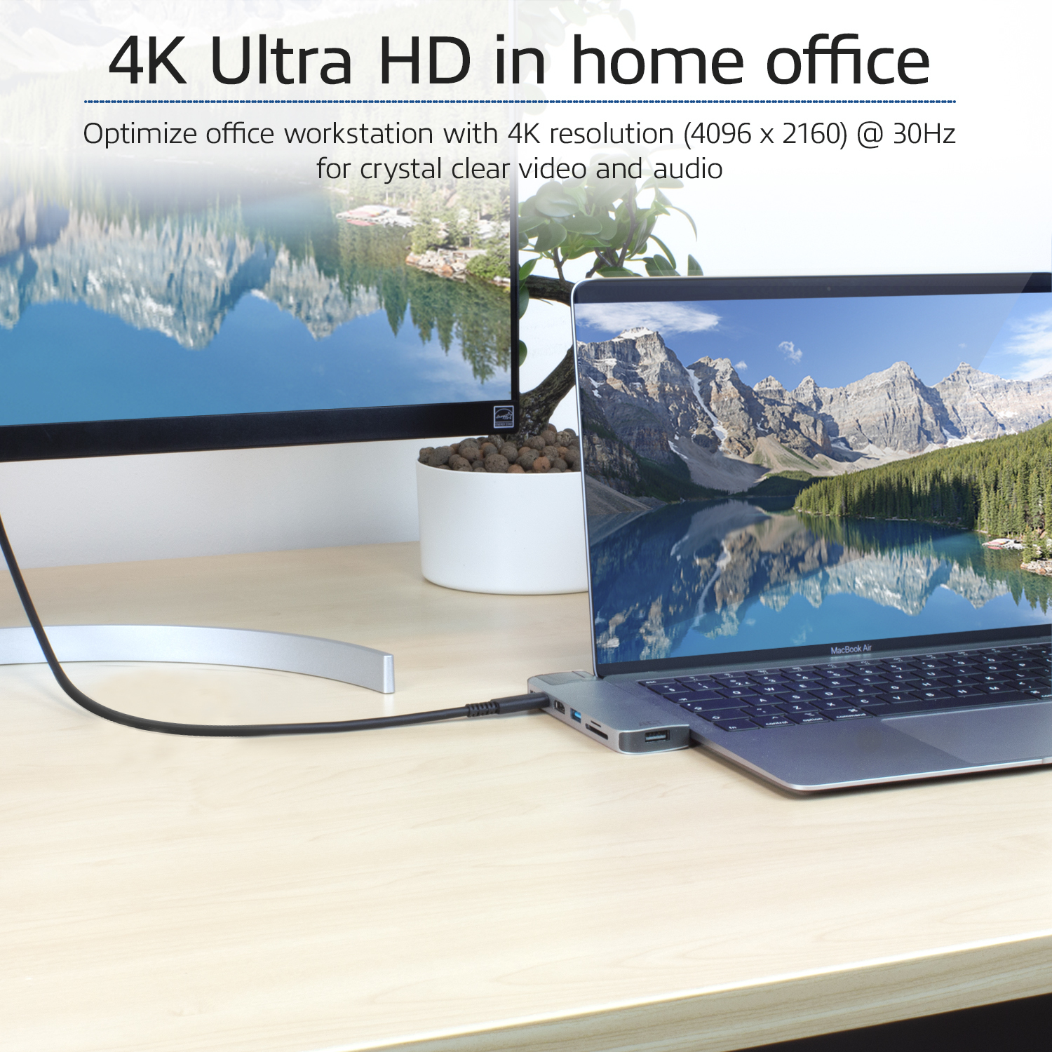 Ein Laptop ist an einen Monitor angeschlossen. Beide zeigen Landschaftsbilder. Es gibt einen Schreibtisch.