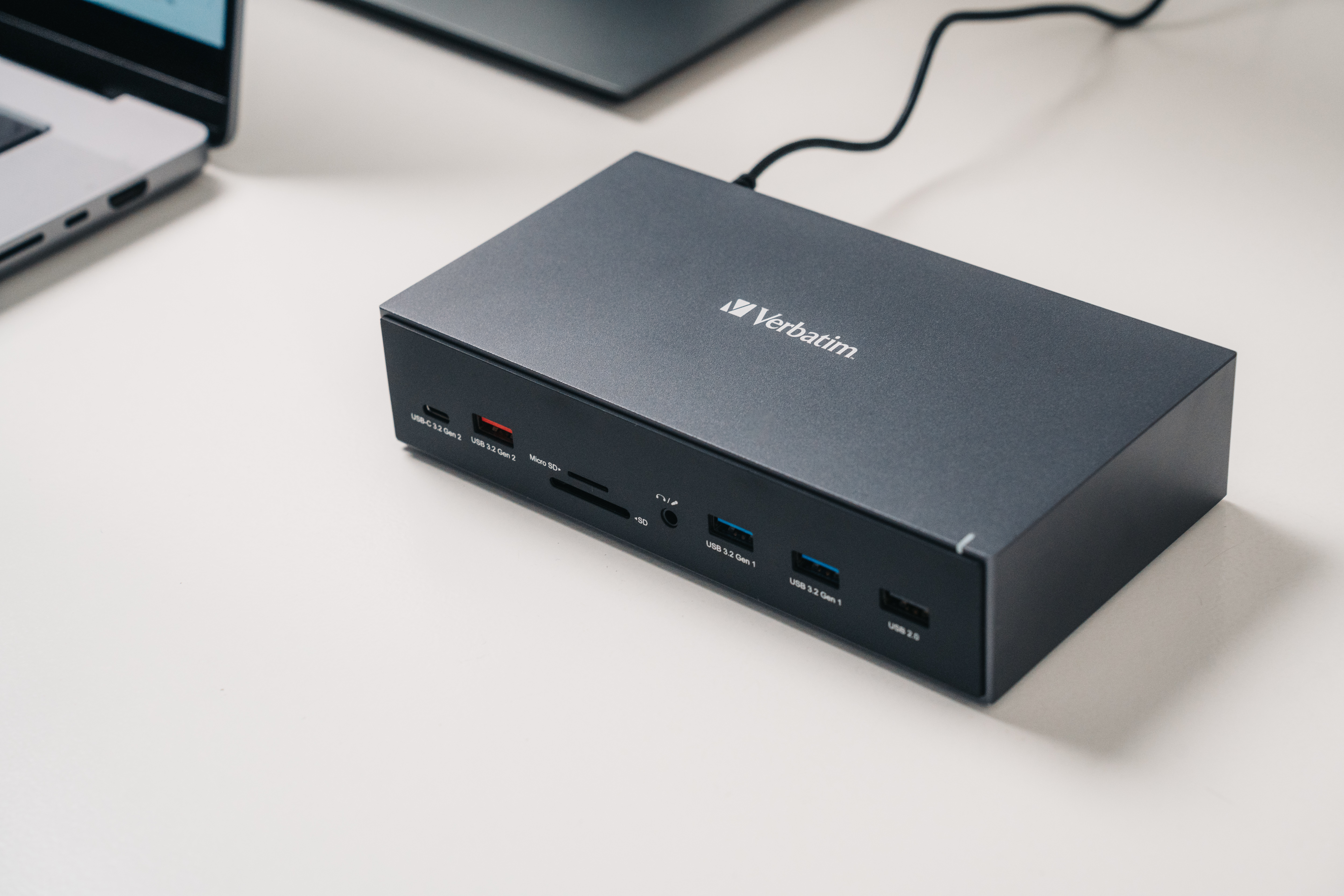 Schwarzes elektronisches Gerät mit Verbatim-Etikett, an einen Laptop angeschlossen. USB-Anschlüsse und Kartenleser sichtbar.