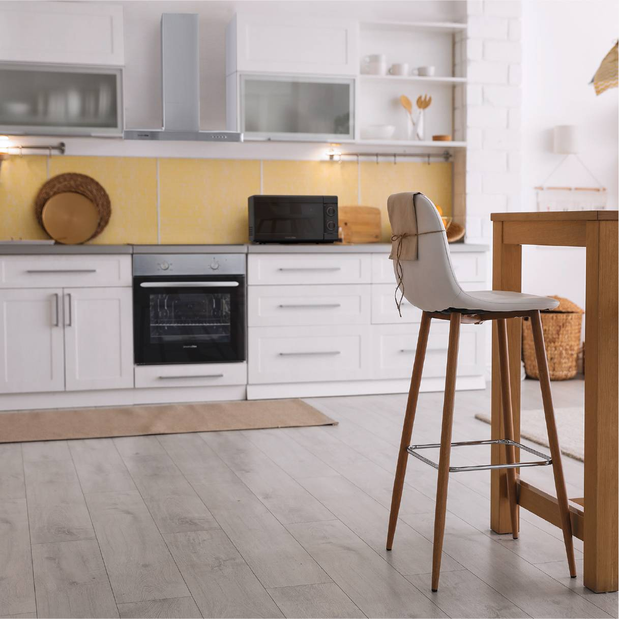 Interior de cocina con gabinetes blancos, silla y microondas.