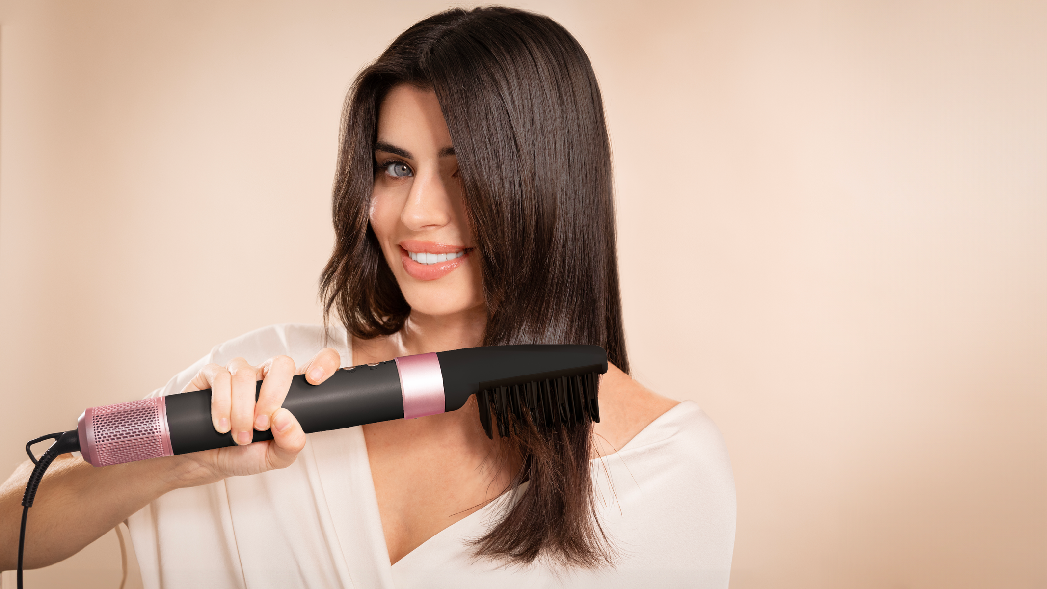 Vrouw die een haarstylingborstel gebruikt, met een lichte achtergrond en focus op het gezicht.