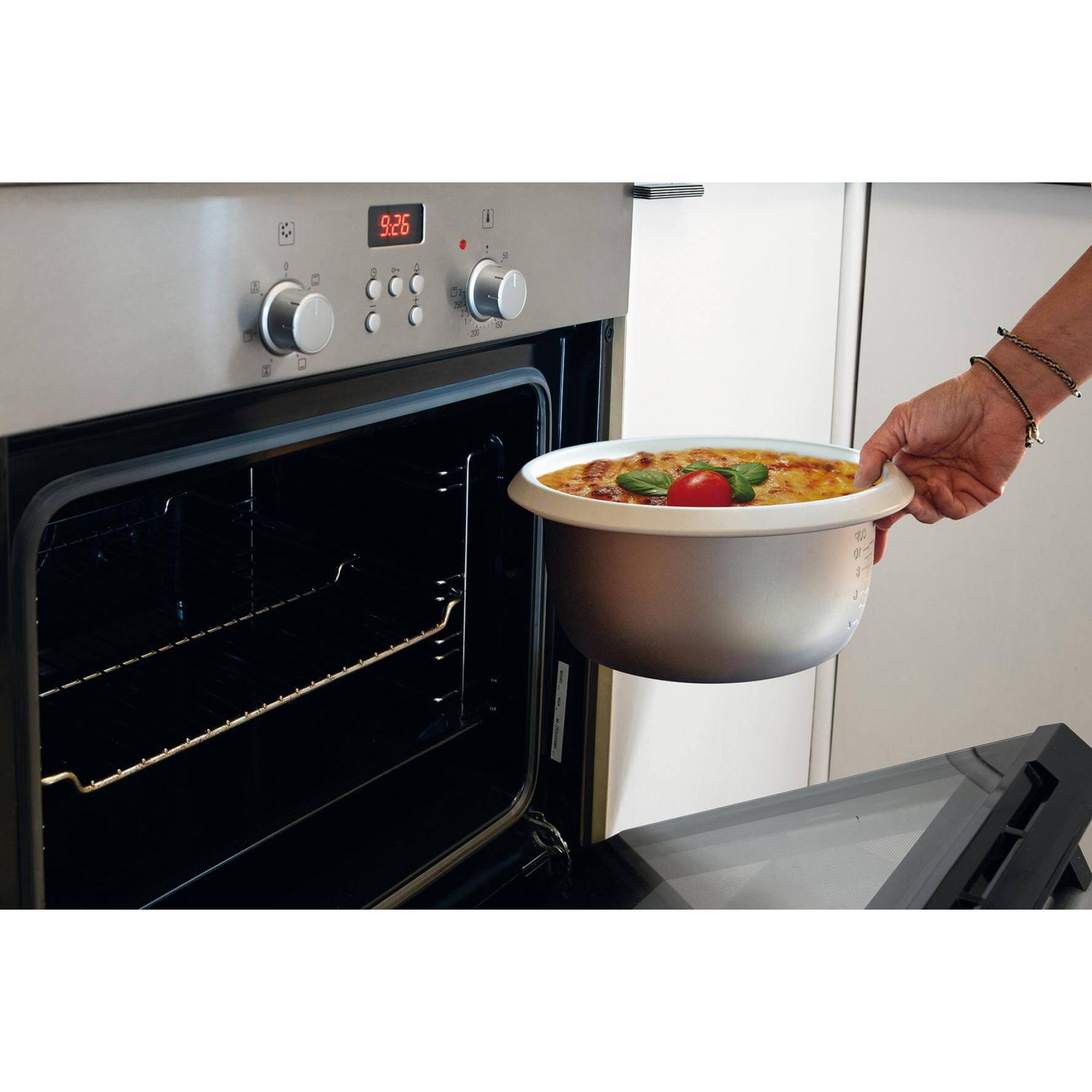 Ręka osoby wyjmuje miskę z jedzeniem z piekarnika; scena kuchenna z wyświetlaczem czasu.