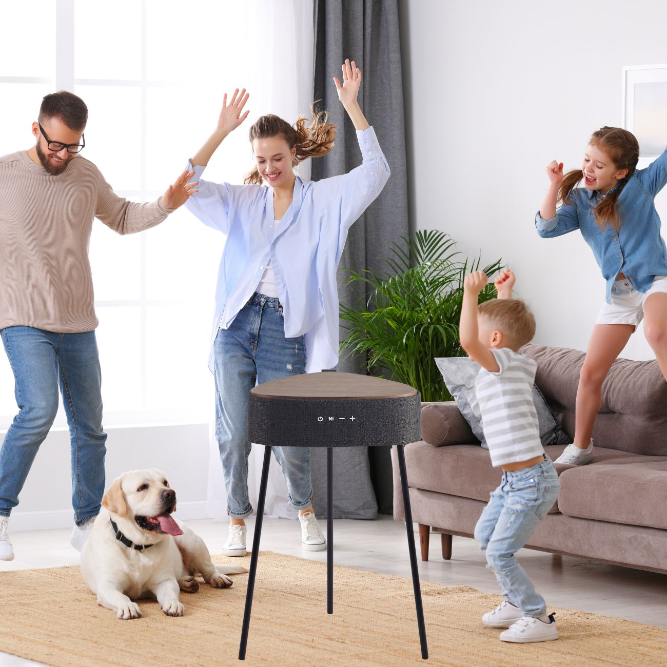 Familie tanzt um Lautsprecher. Hund liegt auf Teppich. Wohnzimmer. Lautsprecher mit Holzplatte.
