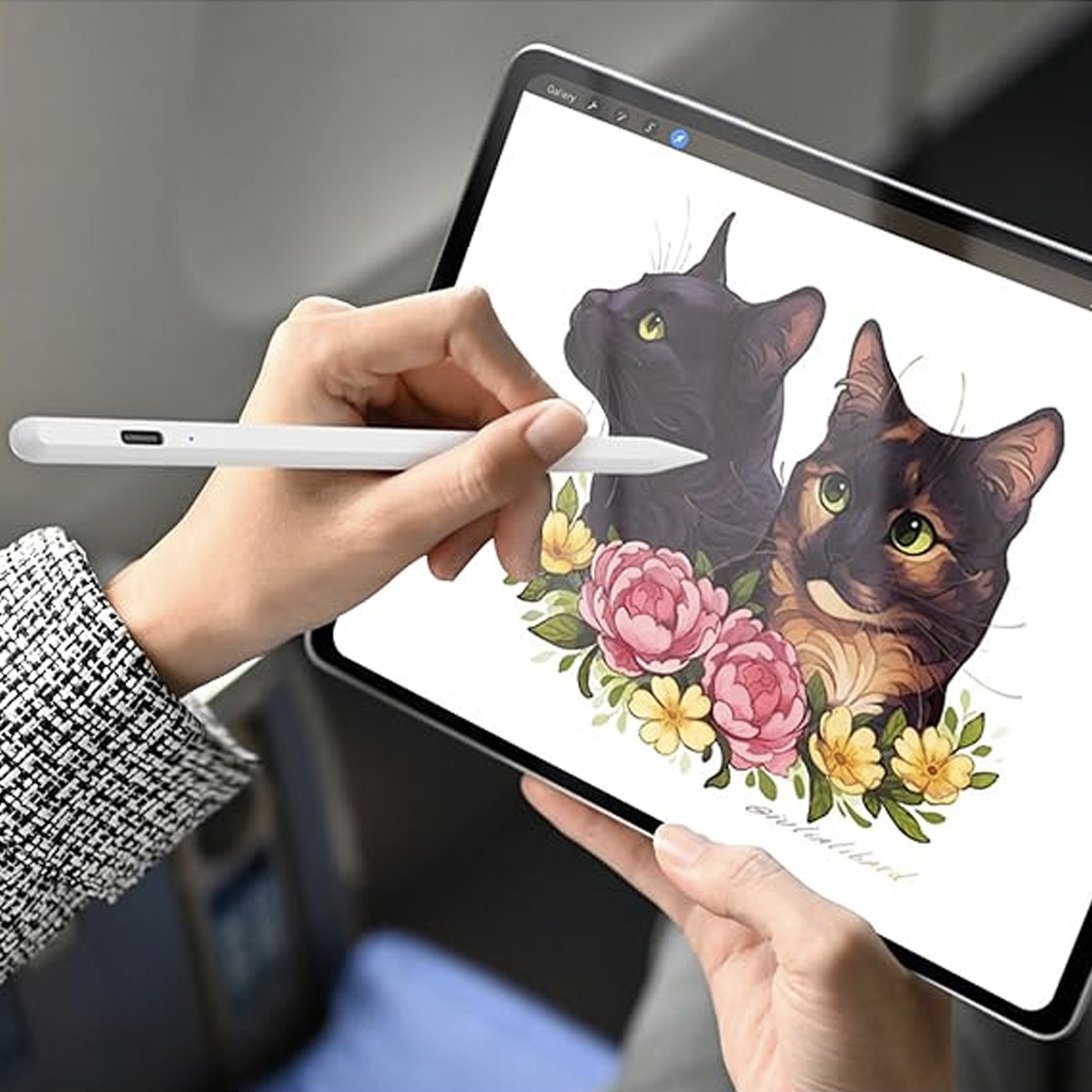 Eine Person benutzt einen weißen Stift auf einem Tablet. Das Tablet zeigt eine Zeichnung von zwei Katzen mit Blumen.