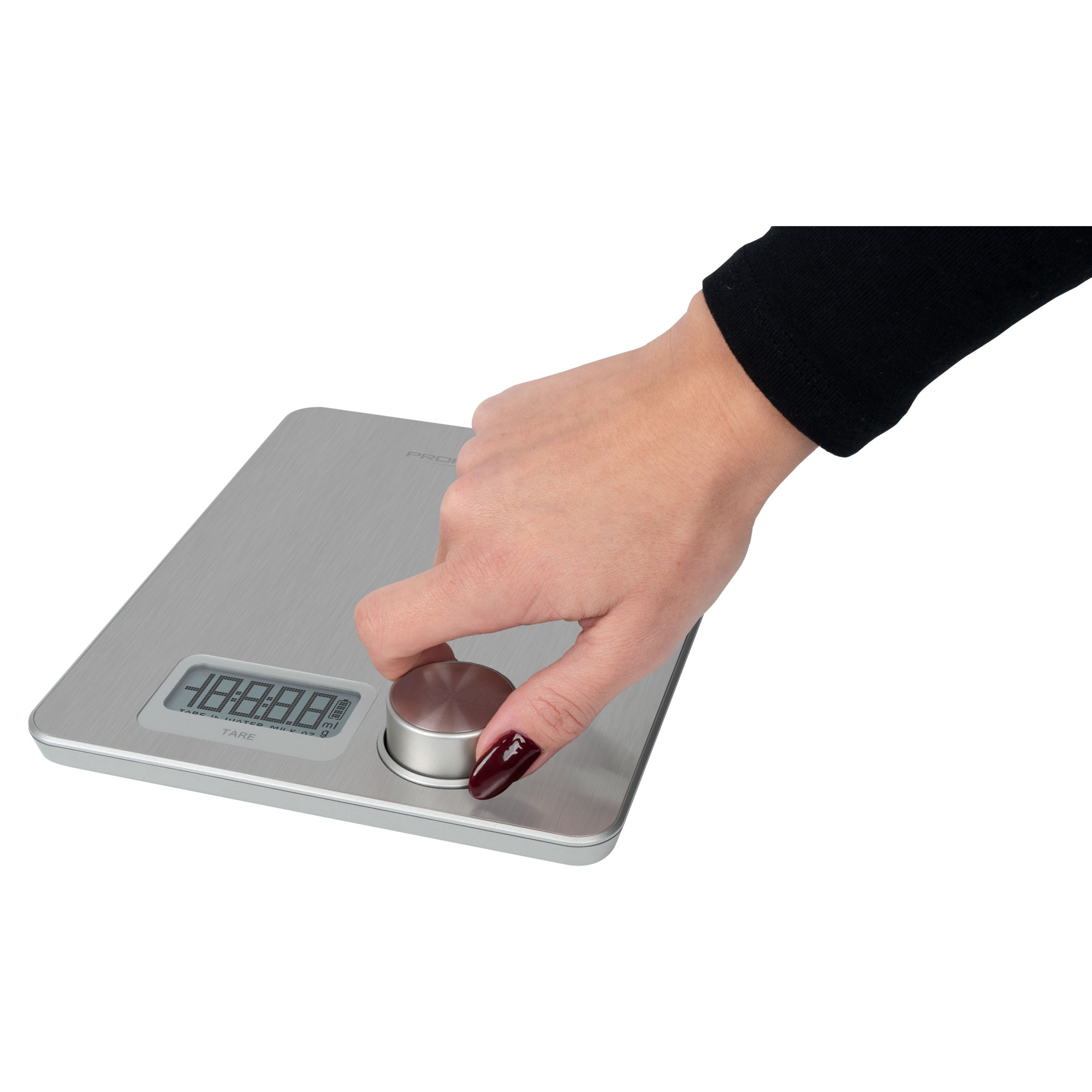 Dłoń obraca pokrętło na srebrnej wadze. Wyświetlacz cyfrowy pokazuje liczby. Białe tło.