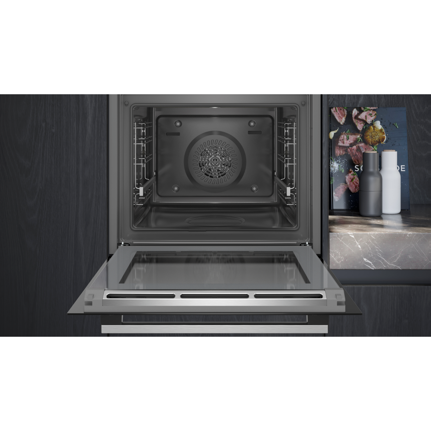 Horno con puerta abierta. Interior gris oscuro. Un libro y botellas están en la encimera.