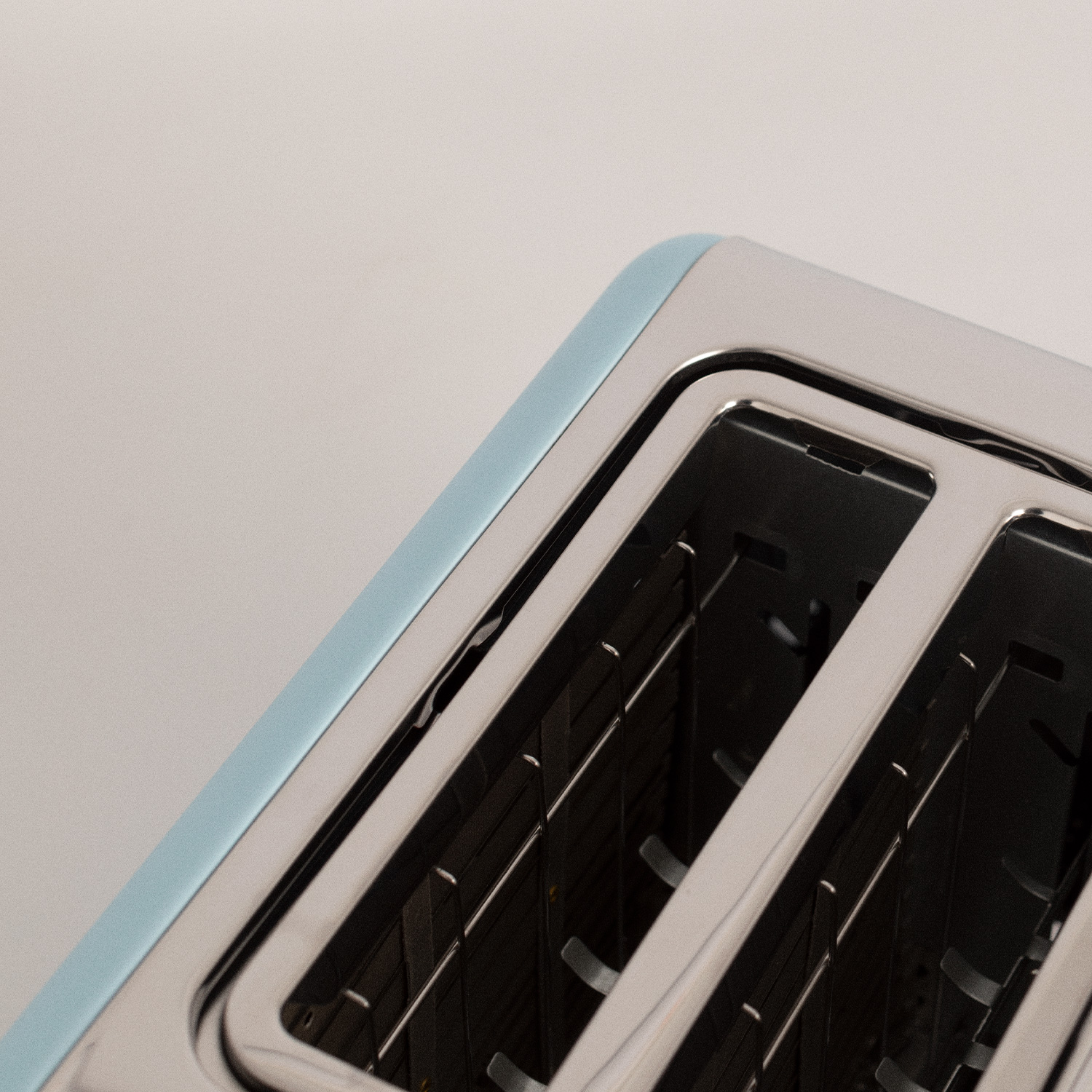 Primer plano de una tostadora azul y plateada que muestra las ranuras y el interior, sobre un fondo blanco.