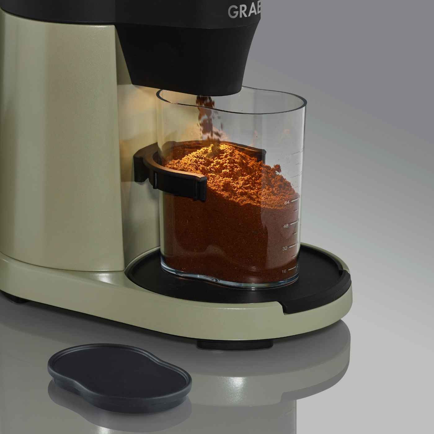 Caffè macinato versato in un contenitore di vetro da una macchina da caffè.