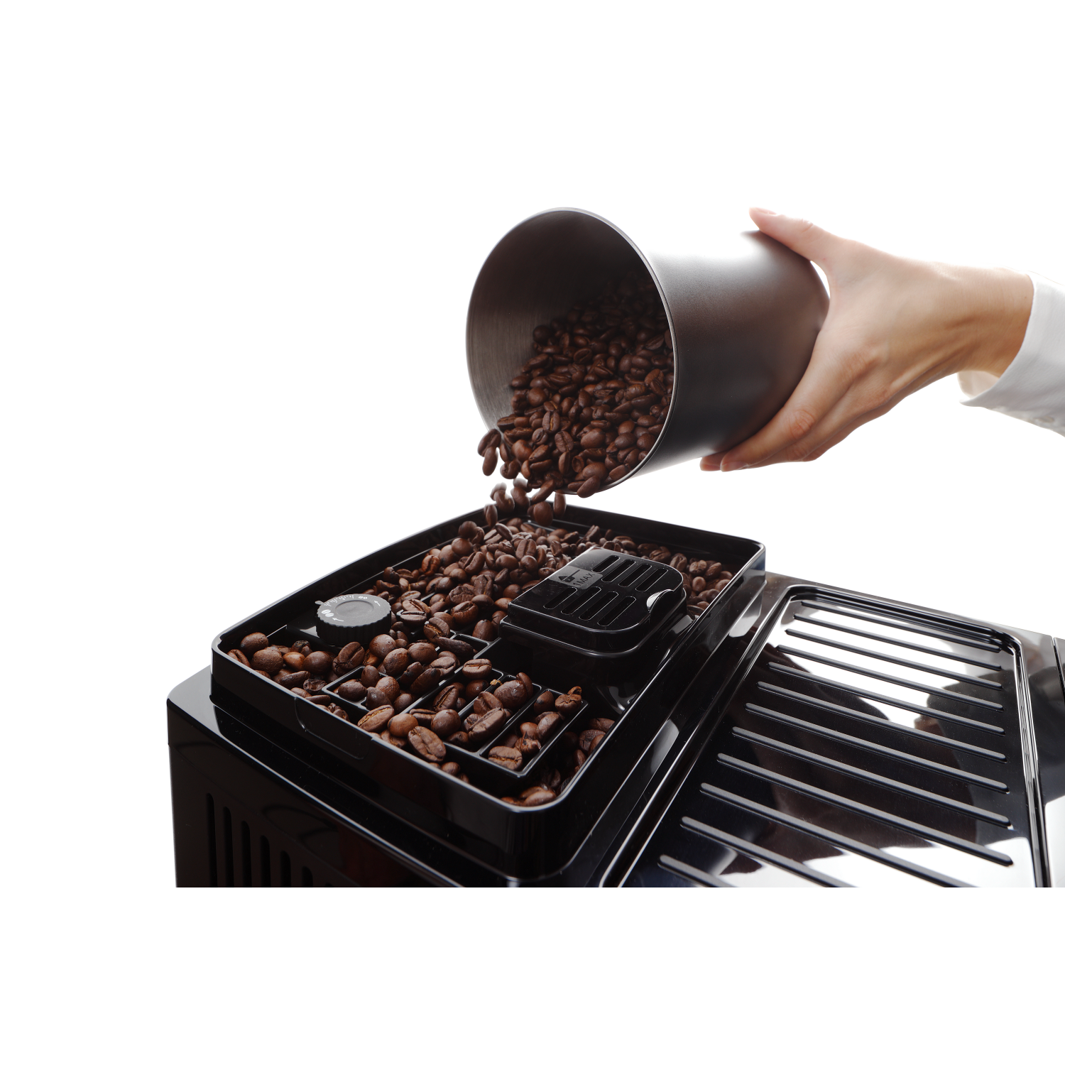 Ręka wsypująca ziarna kawy do zasobnika ekspresu do kawy.