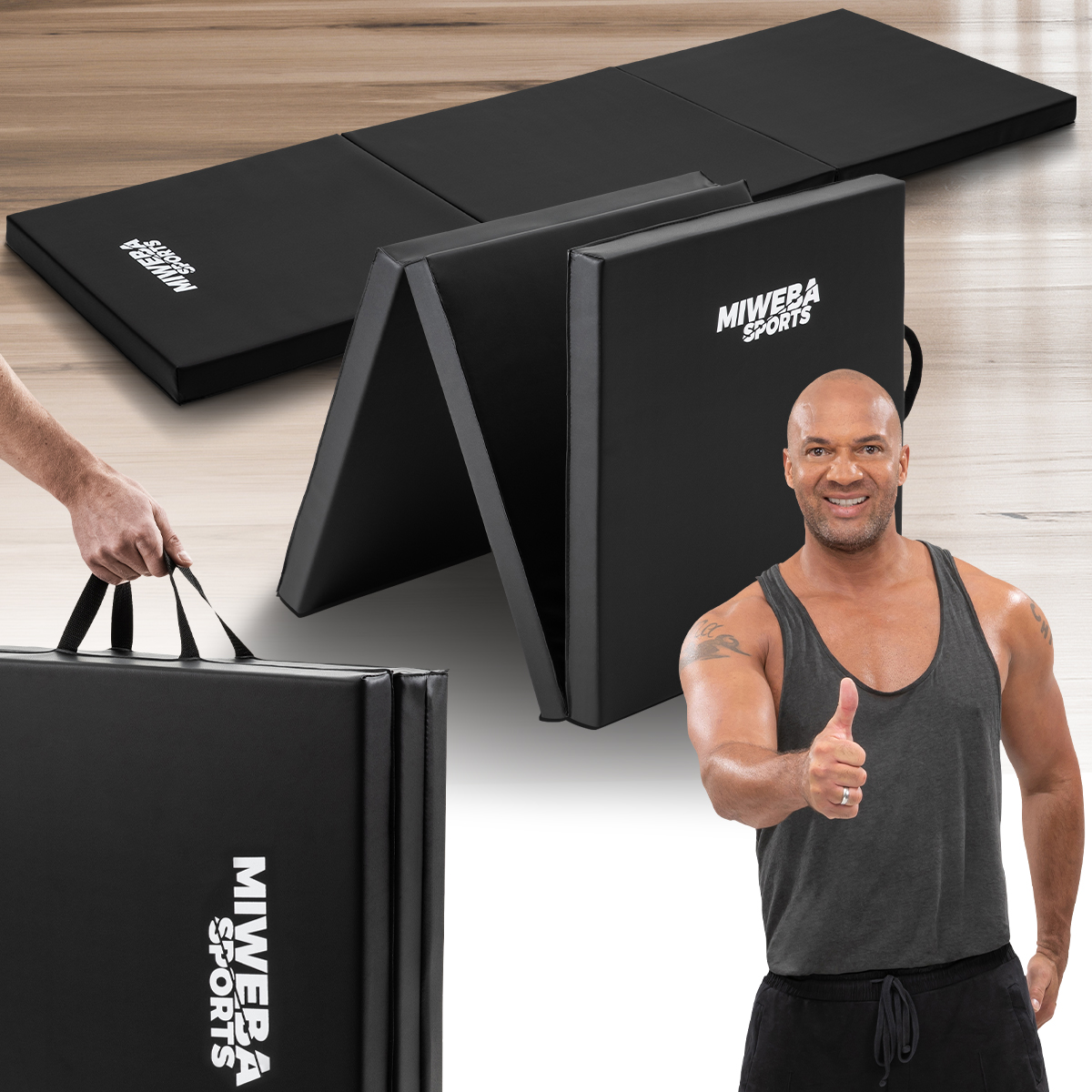 Ein Mann hält eine gefaltete schwarze Trainingsmatte. Eine zweite Matte ist ausgeklappt.