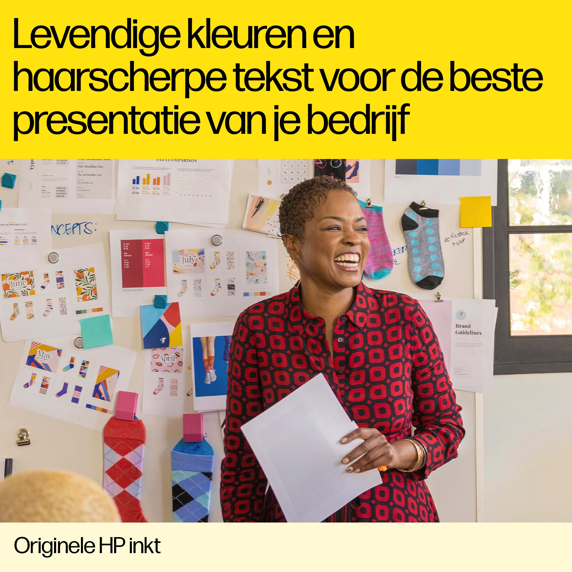 Kobieta trzymająca papier, uśmiechająca się przed ścianą z notatkami, skarpetkami i kolorowymi papierami.