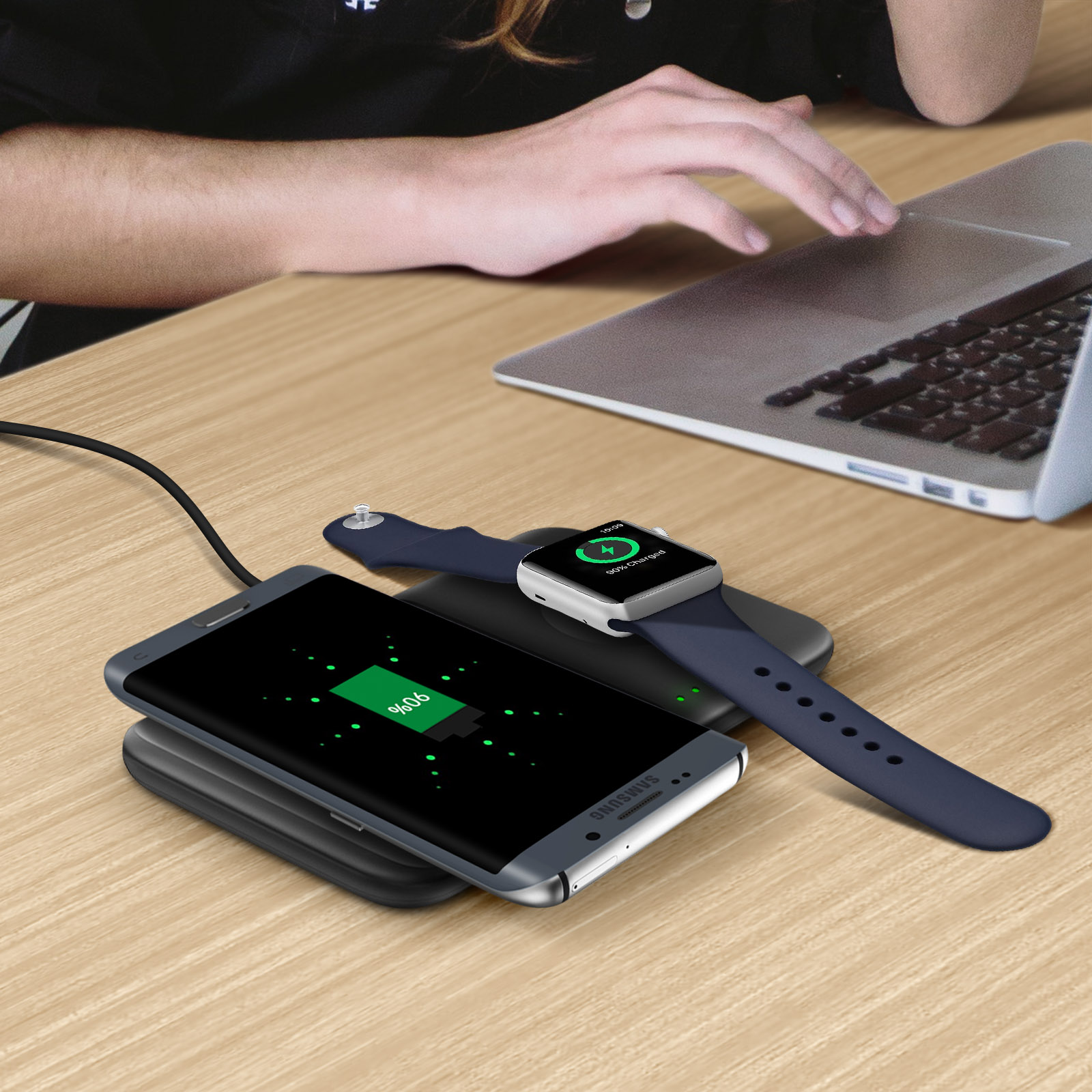 Telefon und Uhr laden auf Pad. Hand einer Frau auf dem Tisch. 90% Ladung.