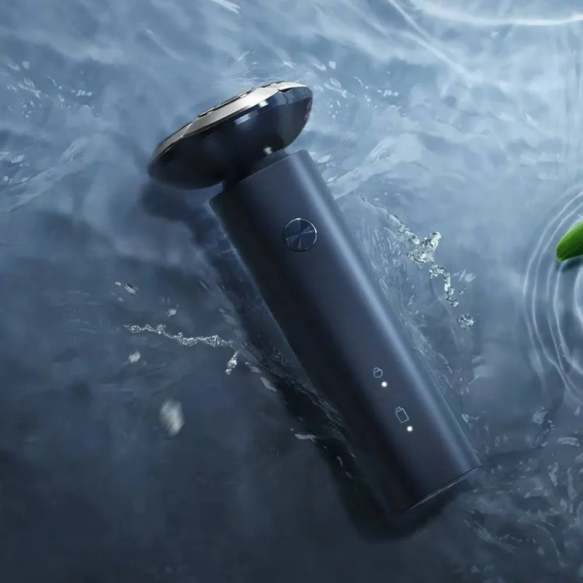 Czarna golarka elektryczna w wodzie, z kroplami wody i błyszczącą metalową krawędzią.