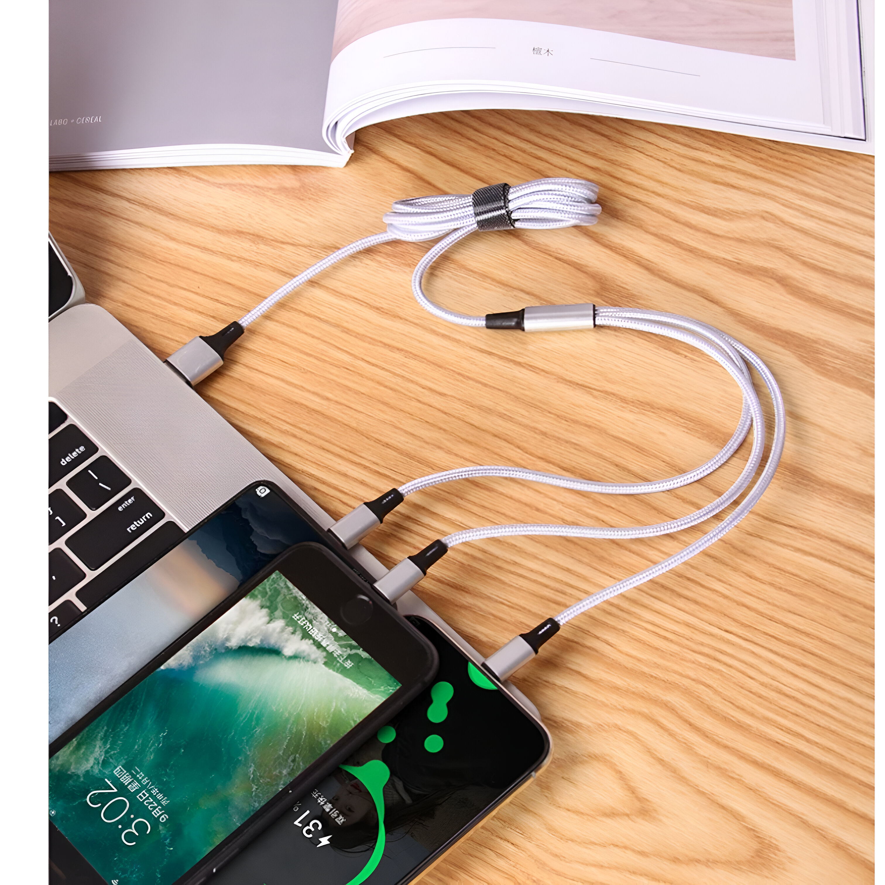 Portátil con dispositivos de carga. Dos teléfonos y un banco de energía conectados por un cable blanco.