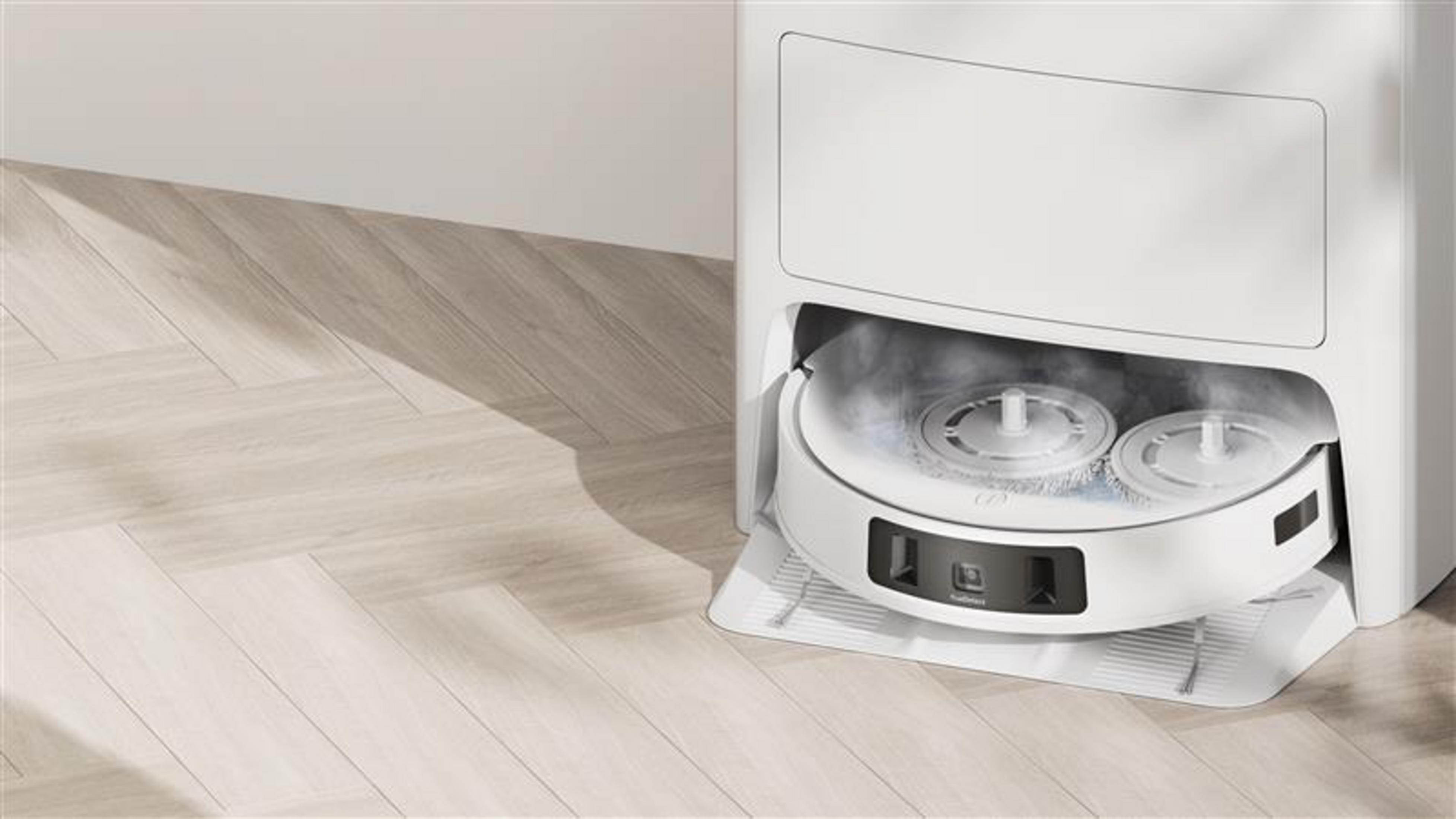 Biały robot sprzątający w stacji czyszczącej na drewnianej podłodze.