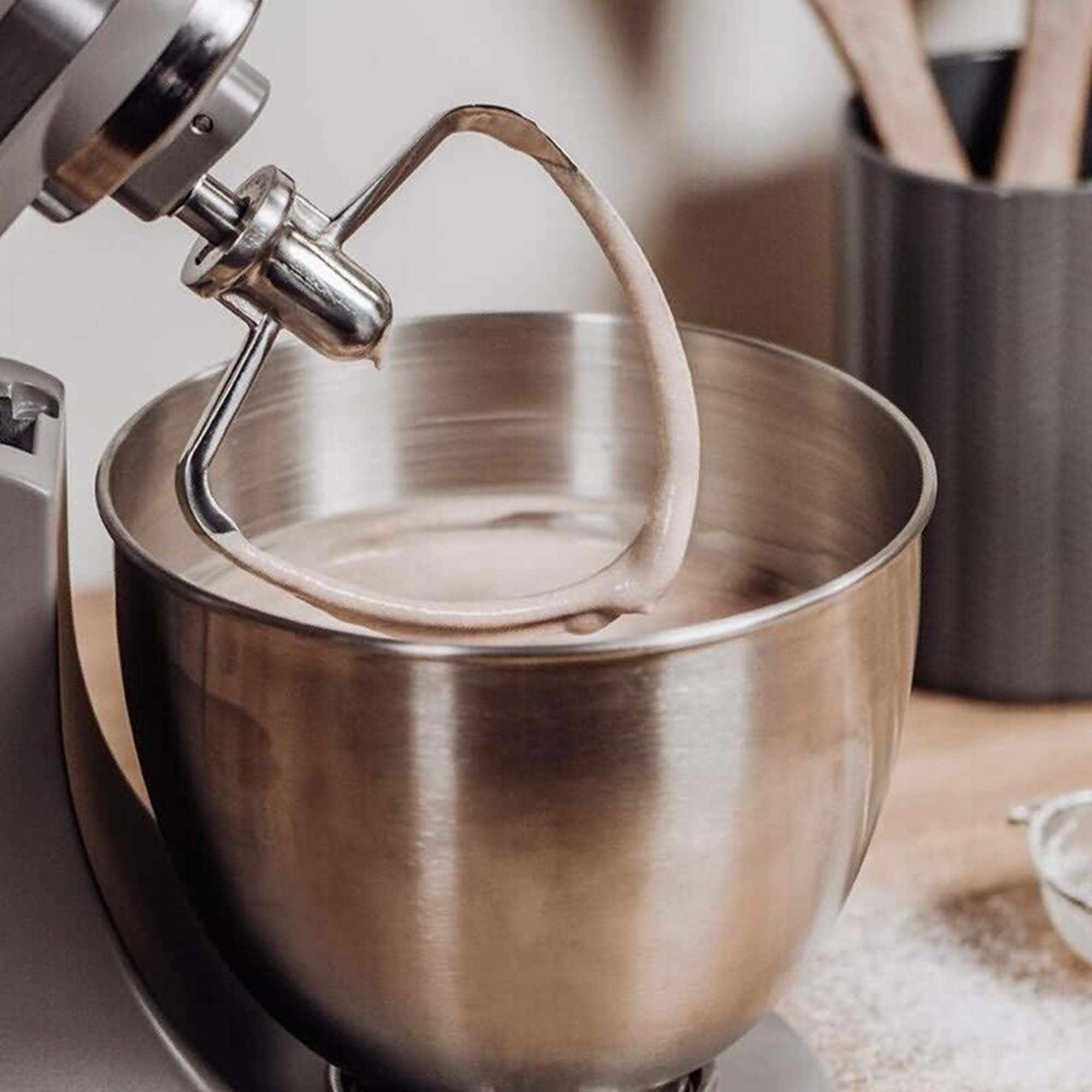 Schüssel der Küchenmaschine mit Teig gefüllt. Rührarm im Teig. Nahaufnahme.