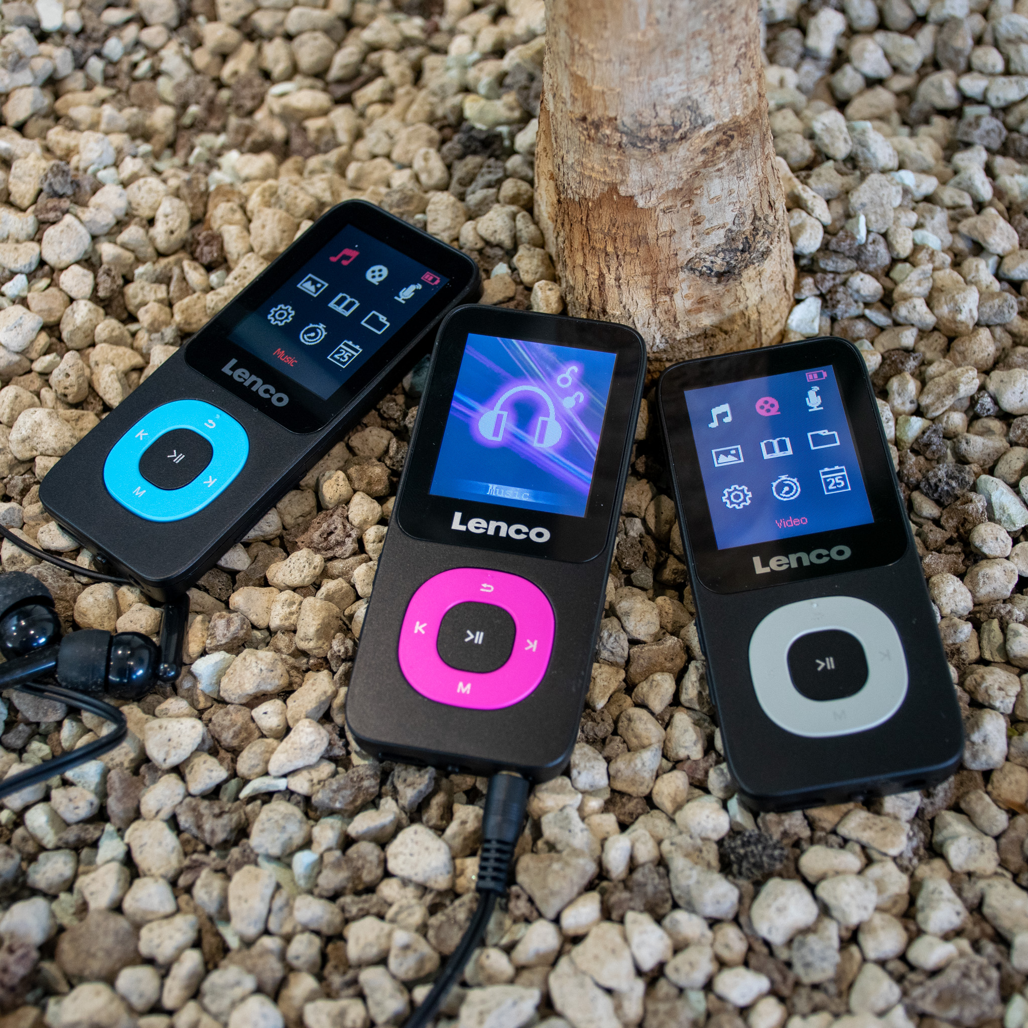 Tre lettori MP3 neri con pulsanti di diversi colori. Sono seduti su piccole rocce.
