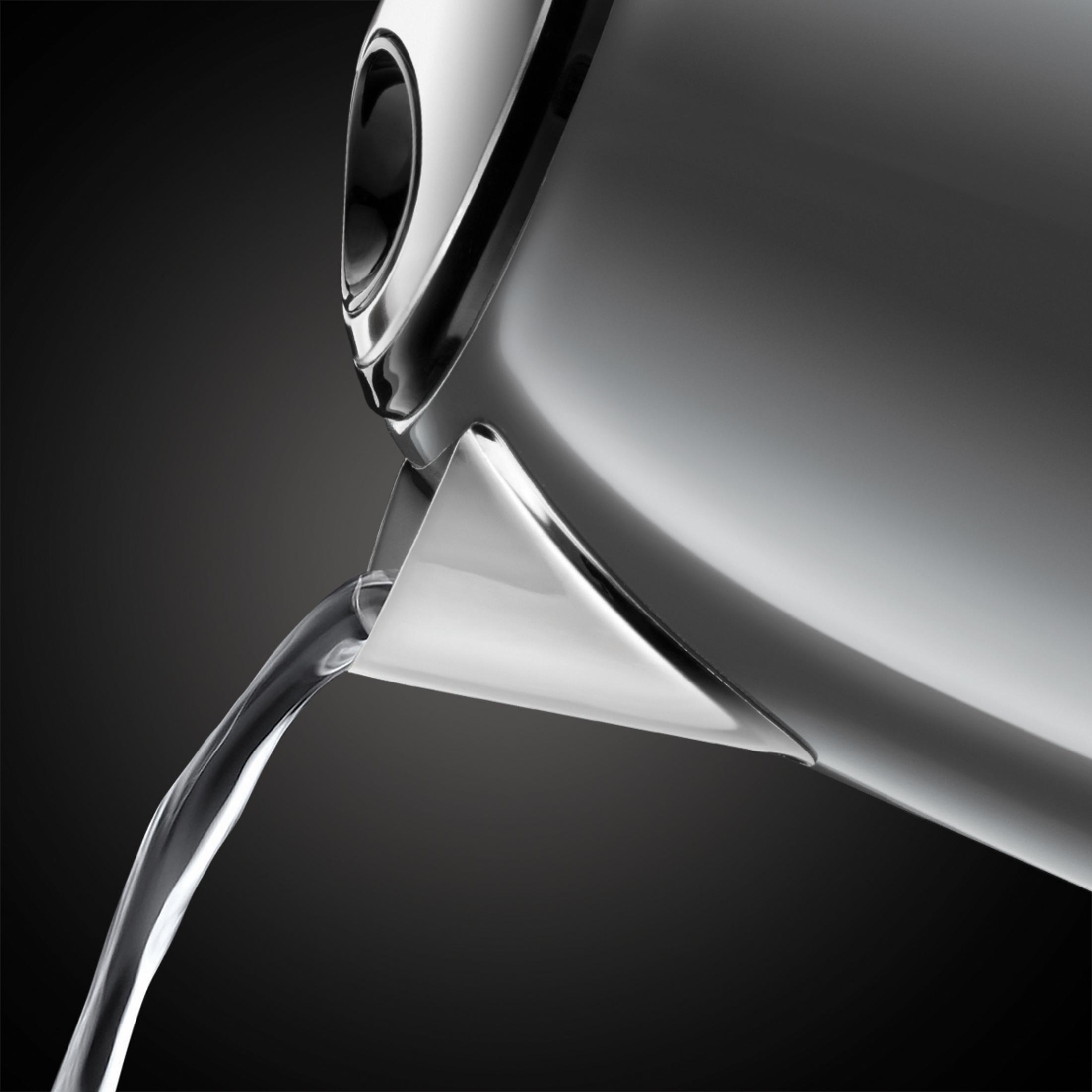 Srebrny czajnik nalewający wodę. Czajnik jest przechylony, woda wypływa z wylewki.