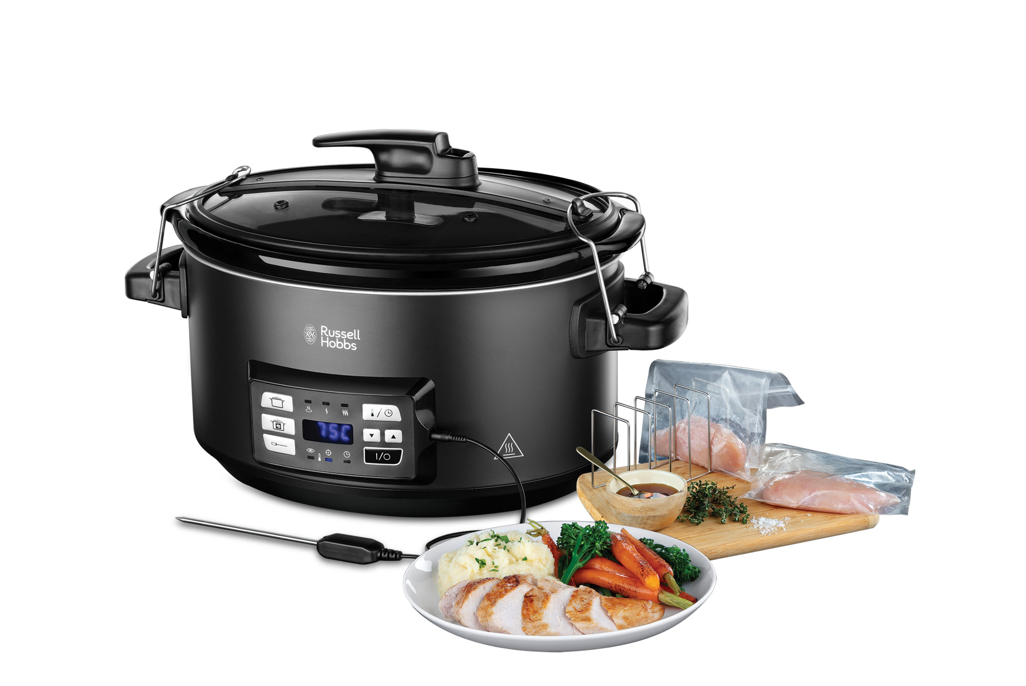Schwarzer Slow Cooker mit Essen auf einem Teller und Zutaten auf einem Schneidebrett, alles auf Weiß.