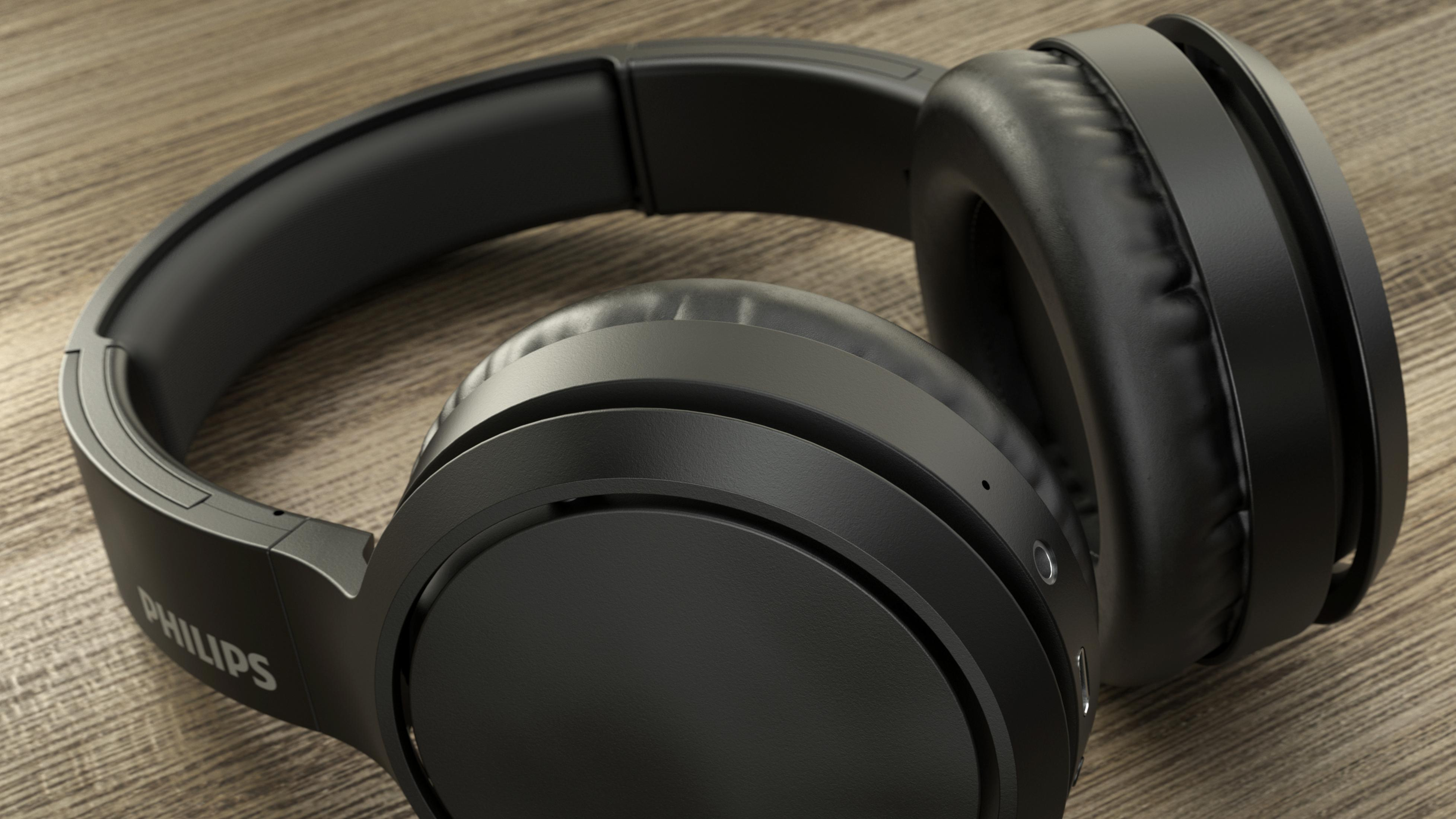 Czarne słuchawki leżą na drewnianej powierzchni, z rozmytym tłem.