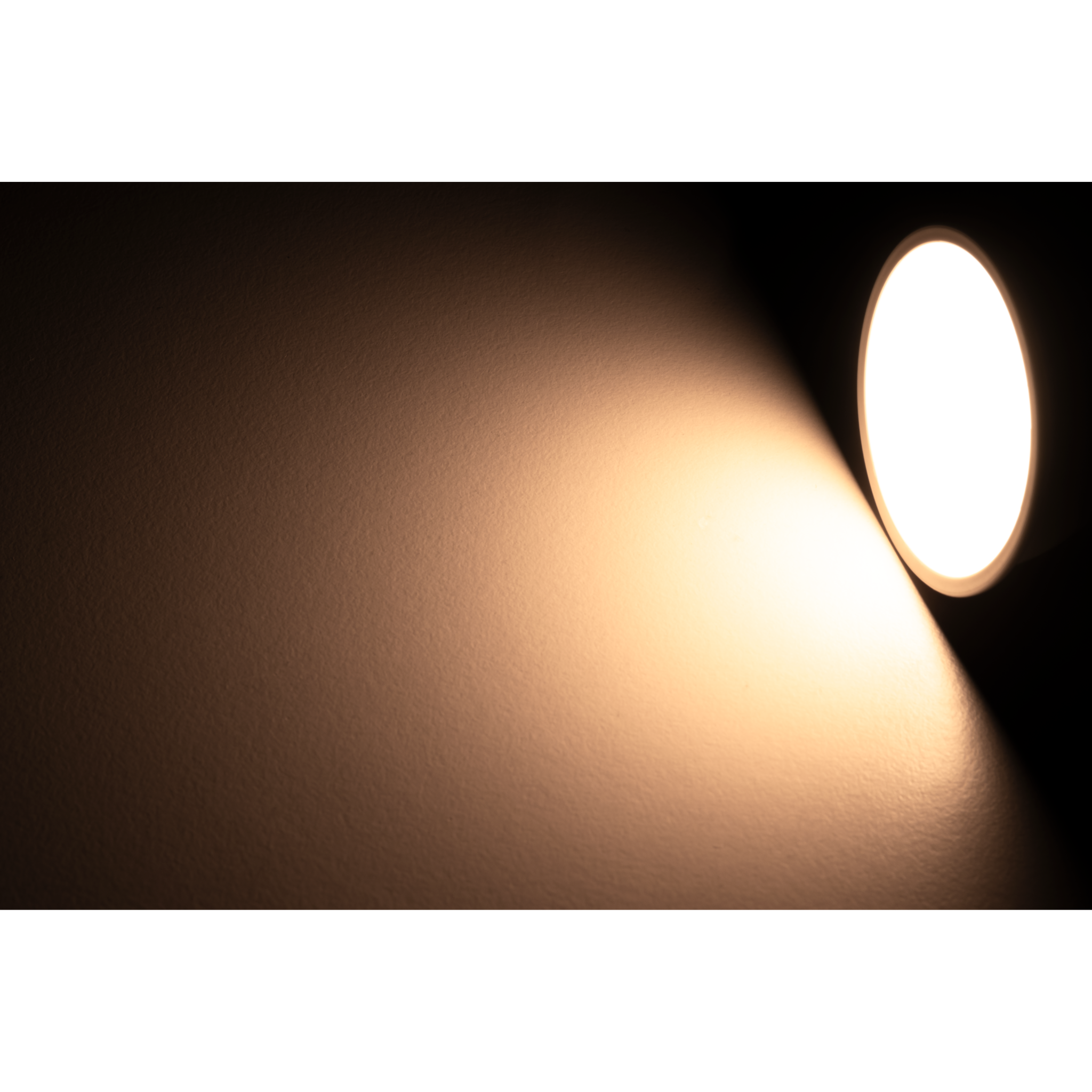Ein Scheinwerfer beleuchtet eine Wand und erzeugt ein helles, kreisförmiges Licht.