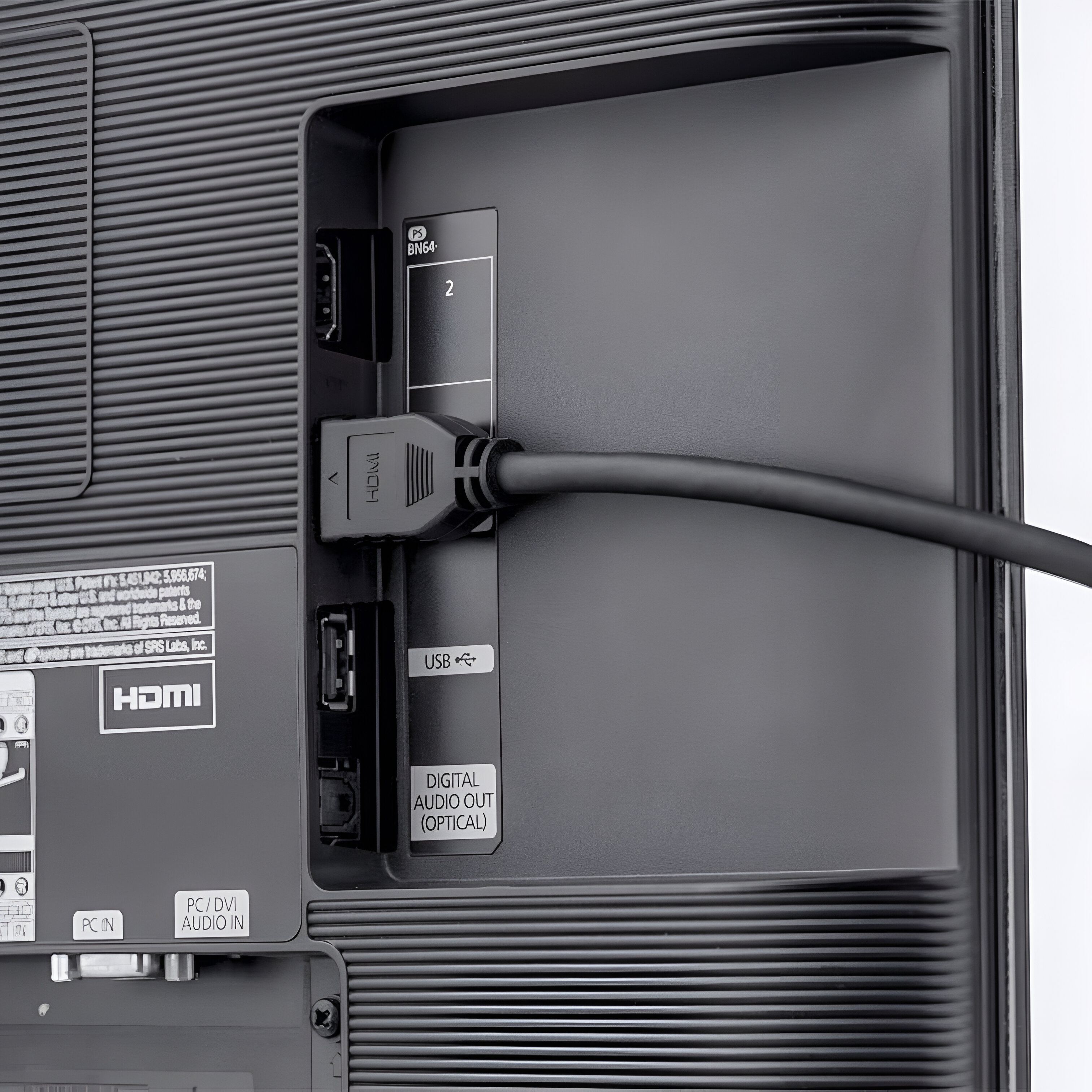 Panel trasero de un televisor negro, con puertos HDMI, USB y salida de audio digital.