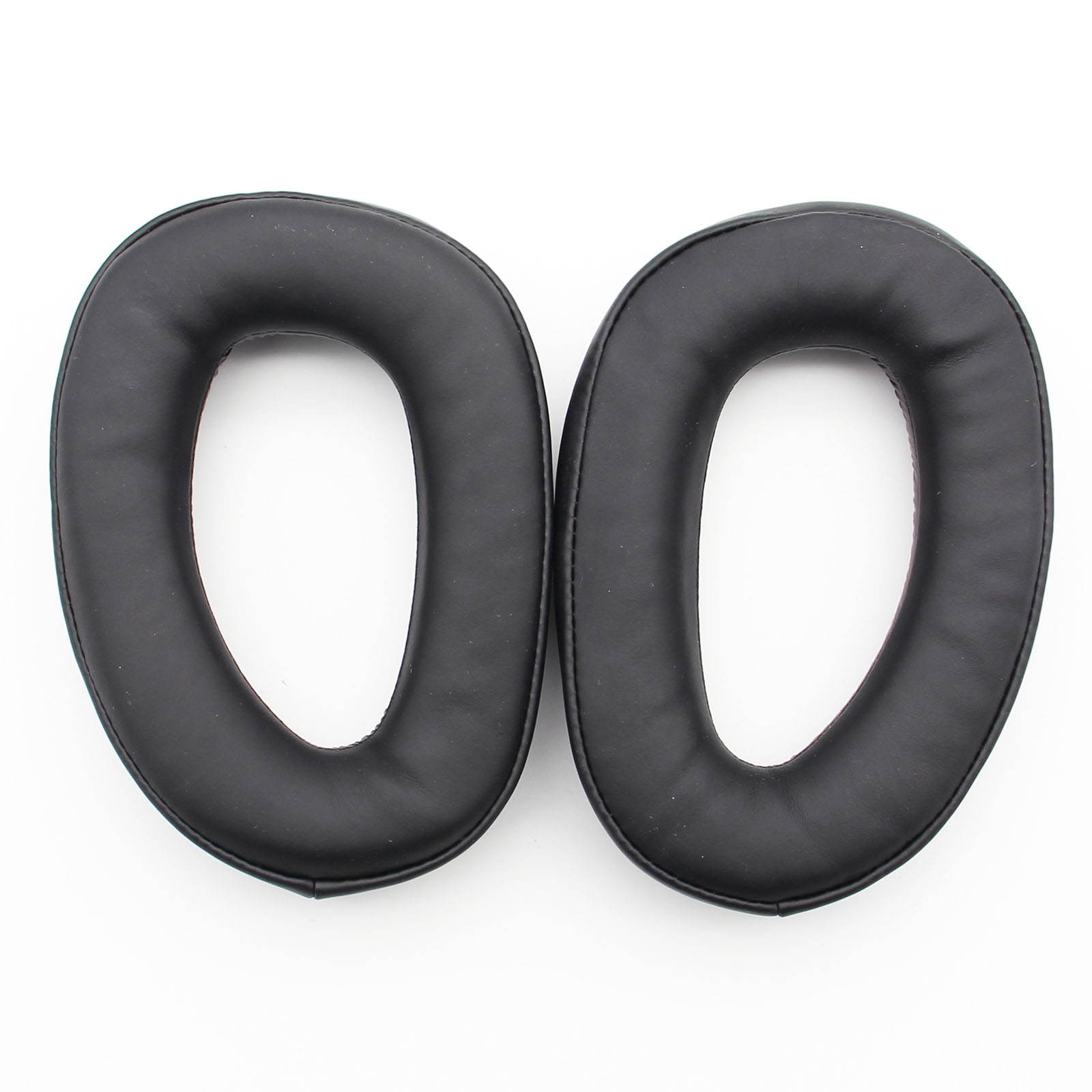 Dwie czarne, owalne nauszniki na białej powierzchni.